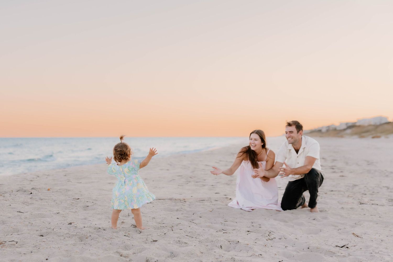 A romantic sunset photo session on a pristine white sand beach with soft pastel colors in the sky.