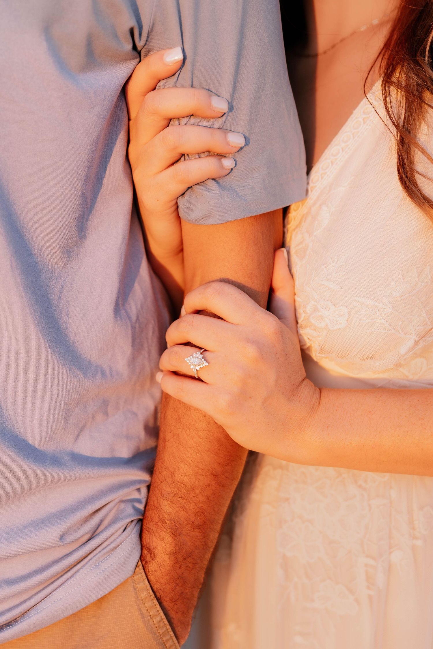 Close-up shots of hands holding and embracing in tender moments against light blue and white fabric backgrounds.