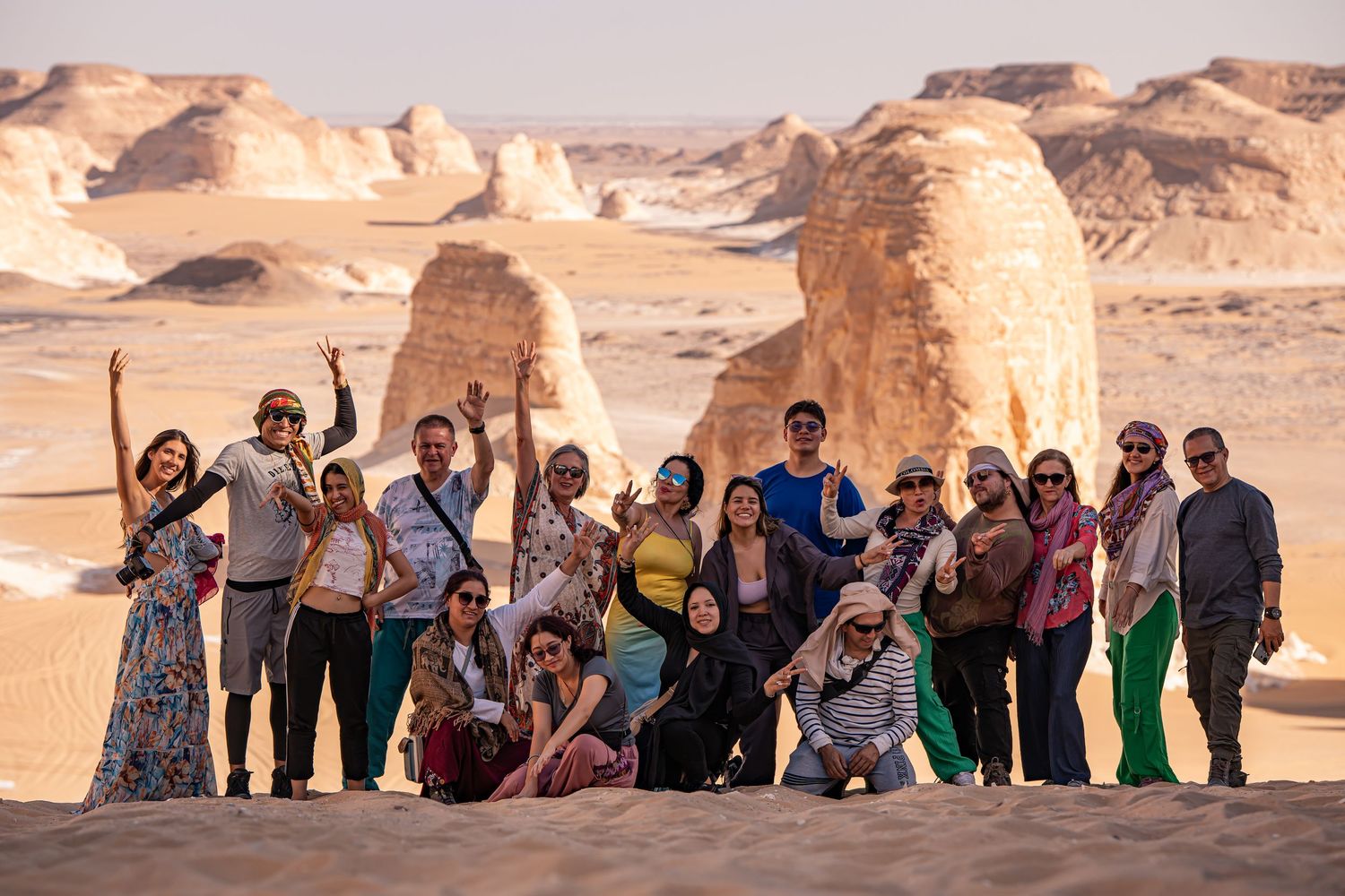 Group of tourists posing together in Egypt's White Desert with limestone rock formations.