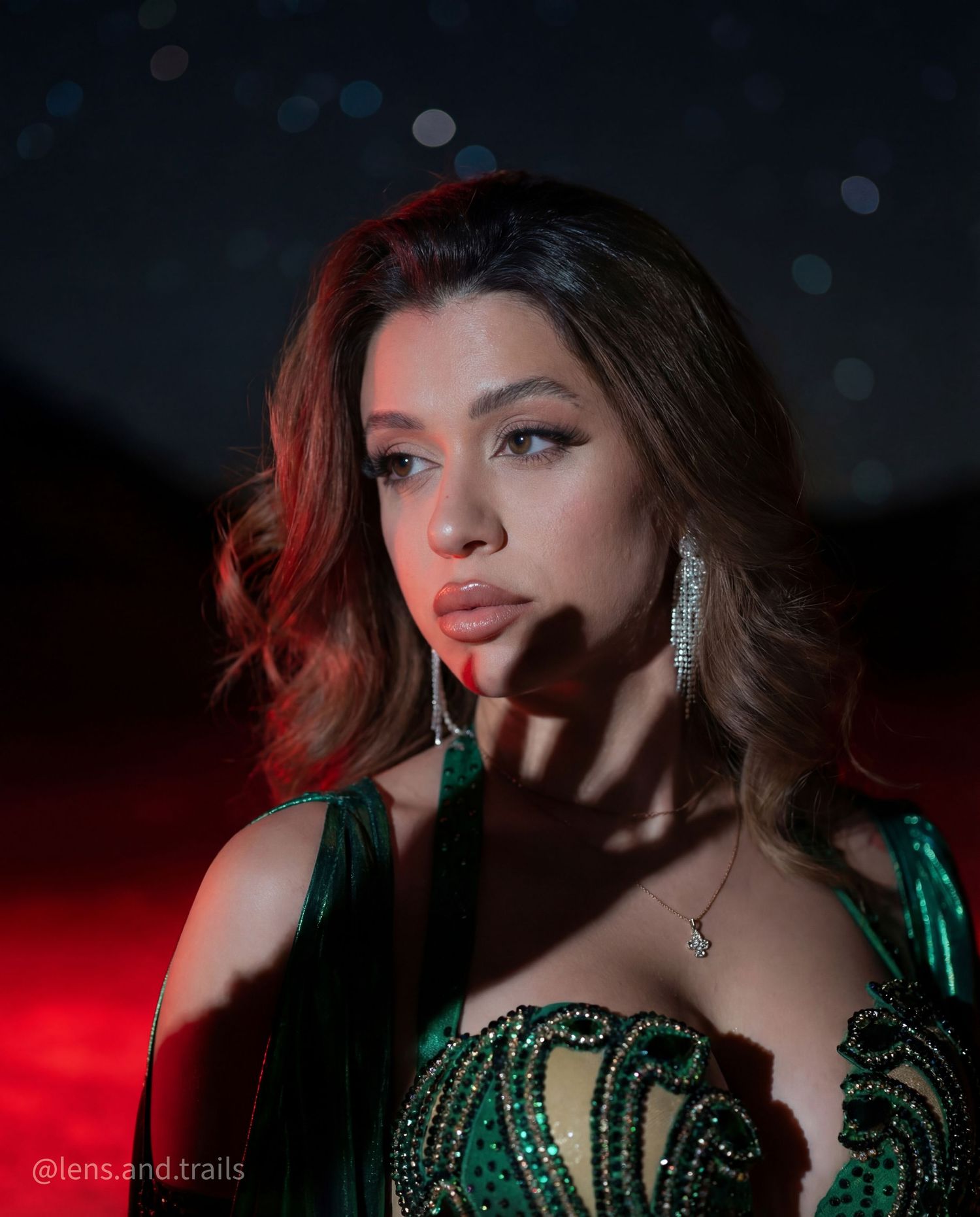 Close-up portrait of young woman in green embellished belly dance costume with elegant earrings and necklace.