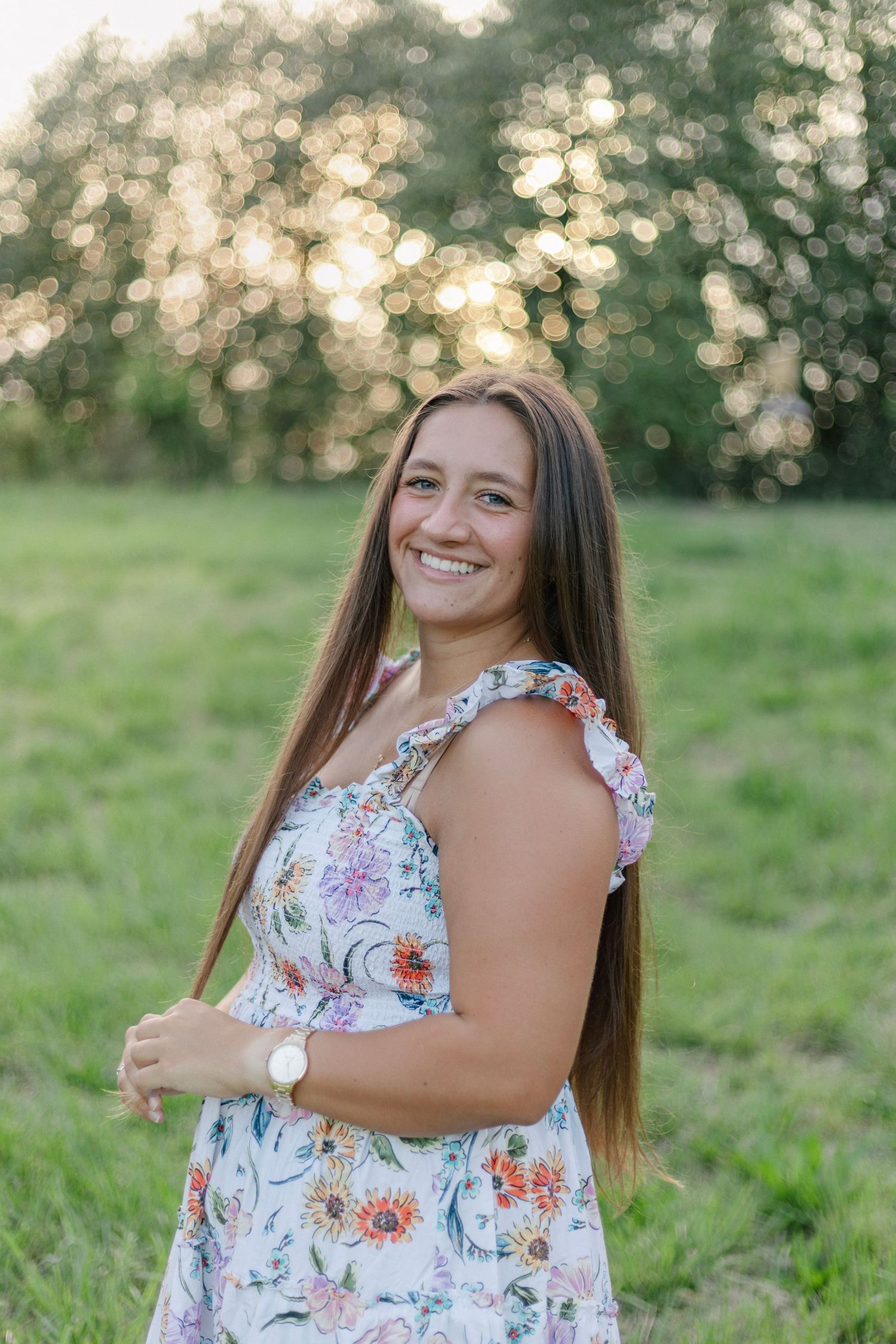 A floral sundress stands out against a blurred sunny background with bokeh lighting effects in a green field.