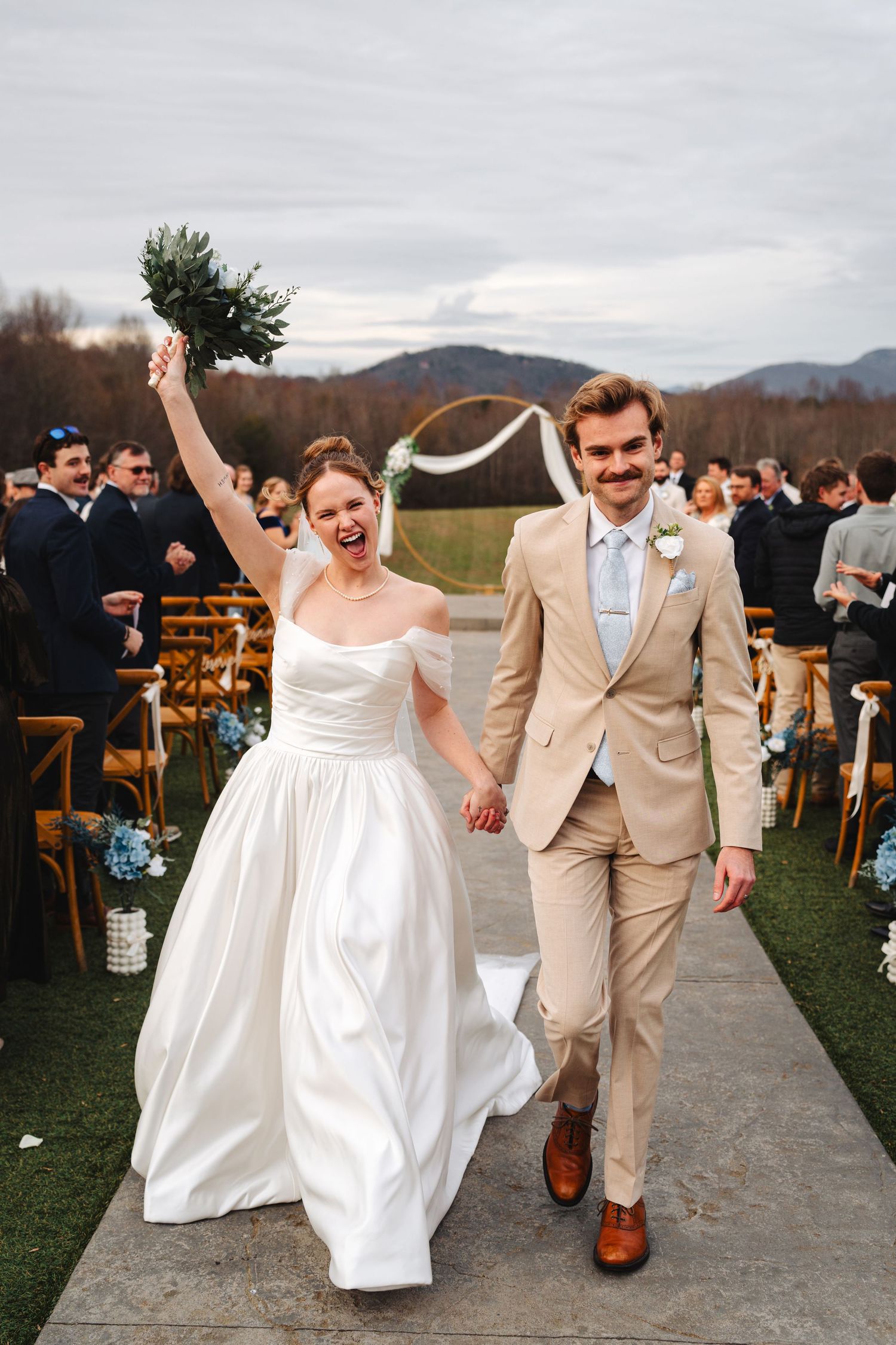 Joyful wedding couple walks back down the aisle at outdoor mountain venue during autumn ceremony.