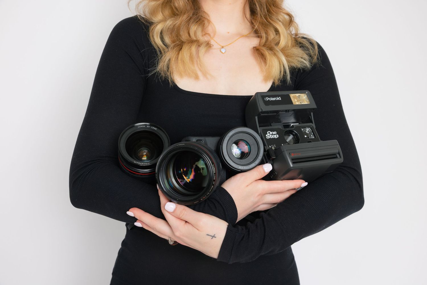 Person in black long sleeve top holding professional digital camera with two camera lenses.