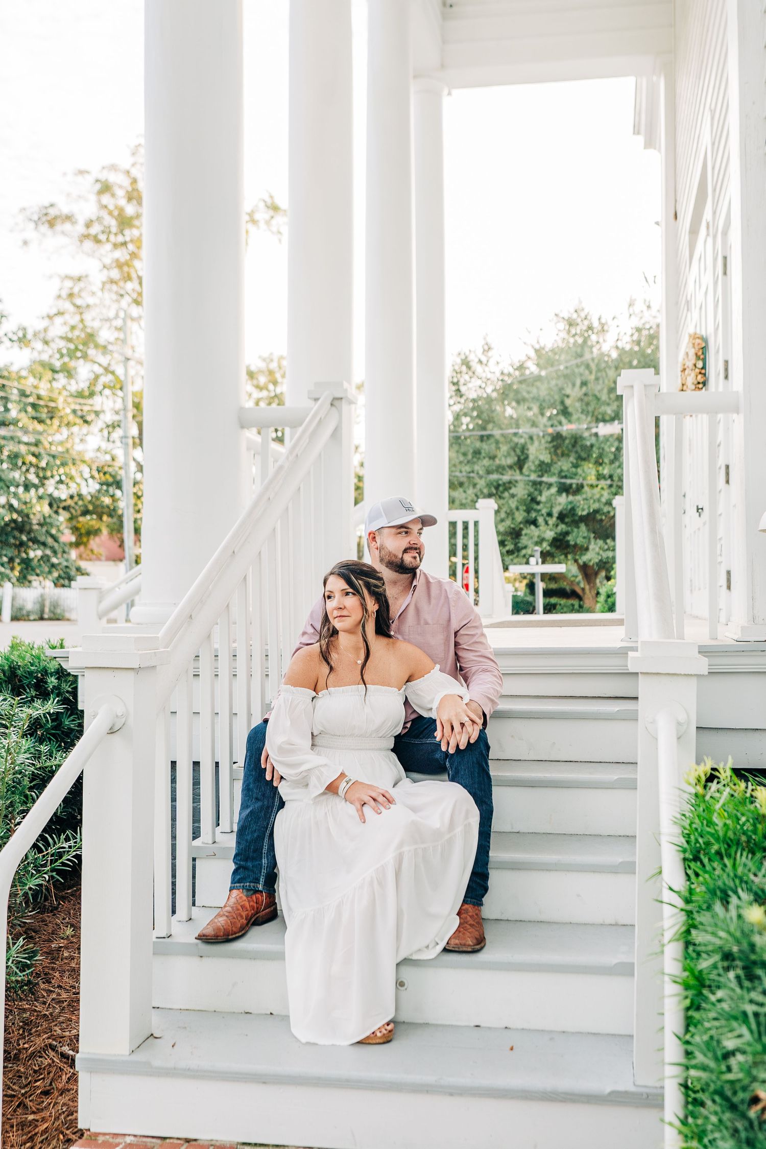 Romantic couple photos on white porch steps of Southern style home with columns.