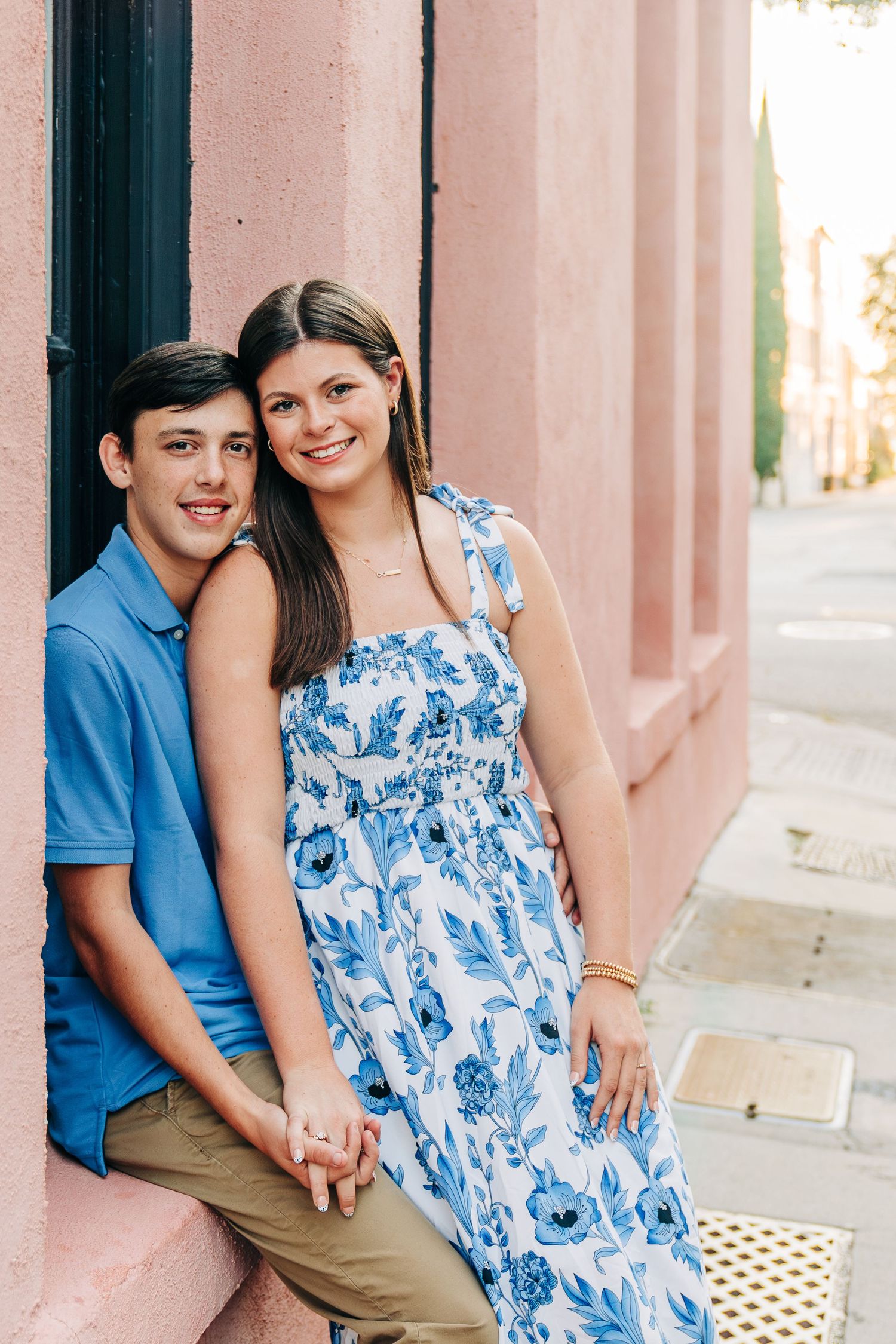 Couple posing against pink wall wearing coordinating blue outfits.