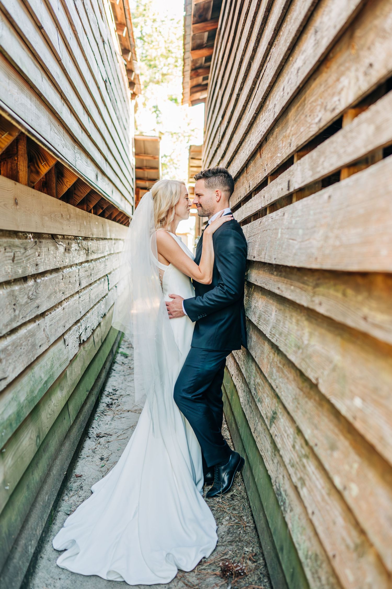 Wedding couple posing in rustic wooden architectural setting.