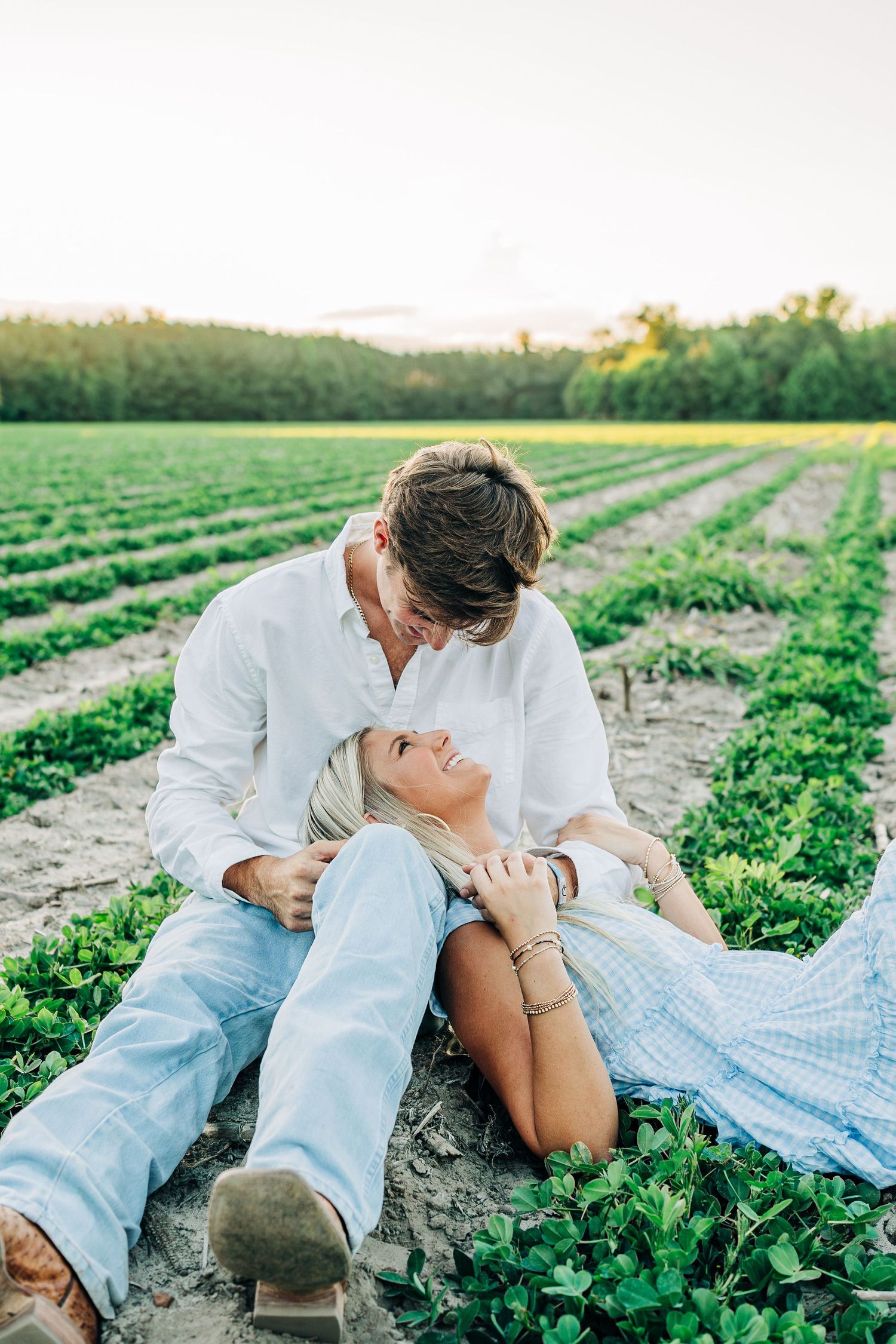 Romantic couple laying in a green agricultural field during sunset.