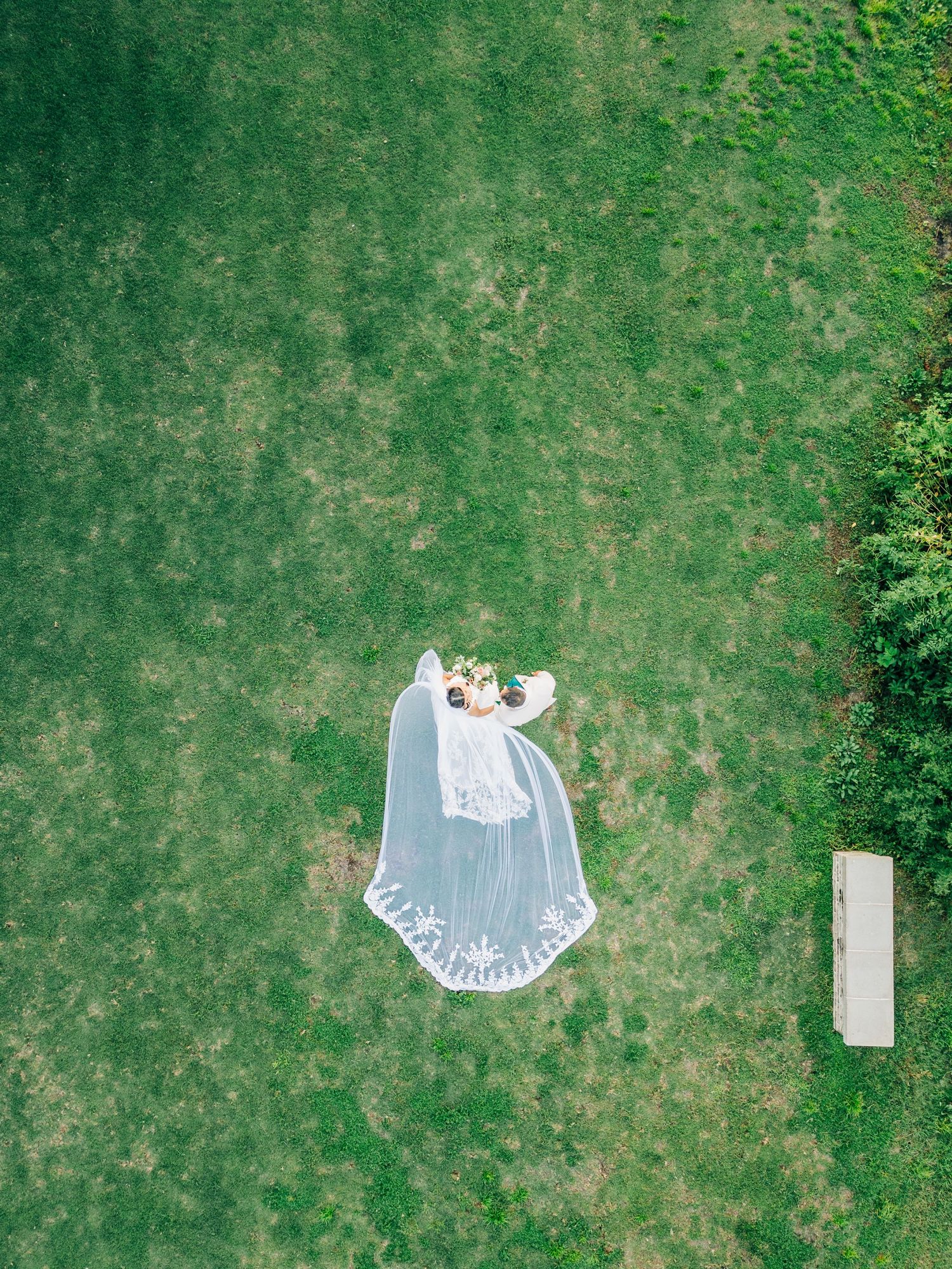 Drone shot of white wedding dress laid out on green lawn.