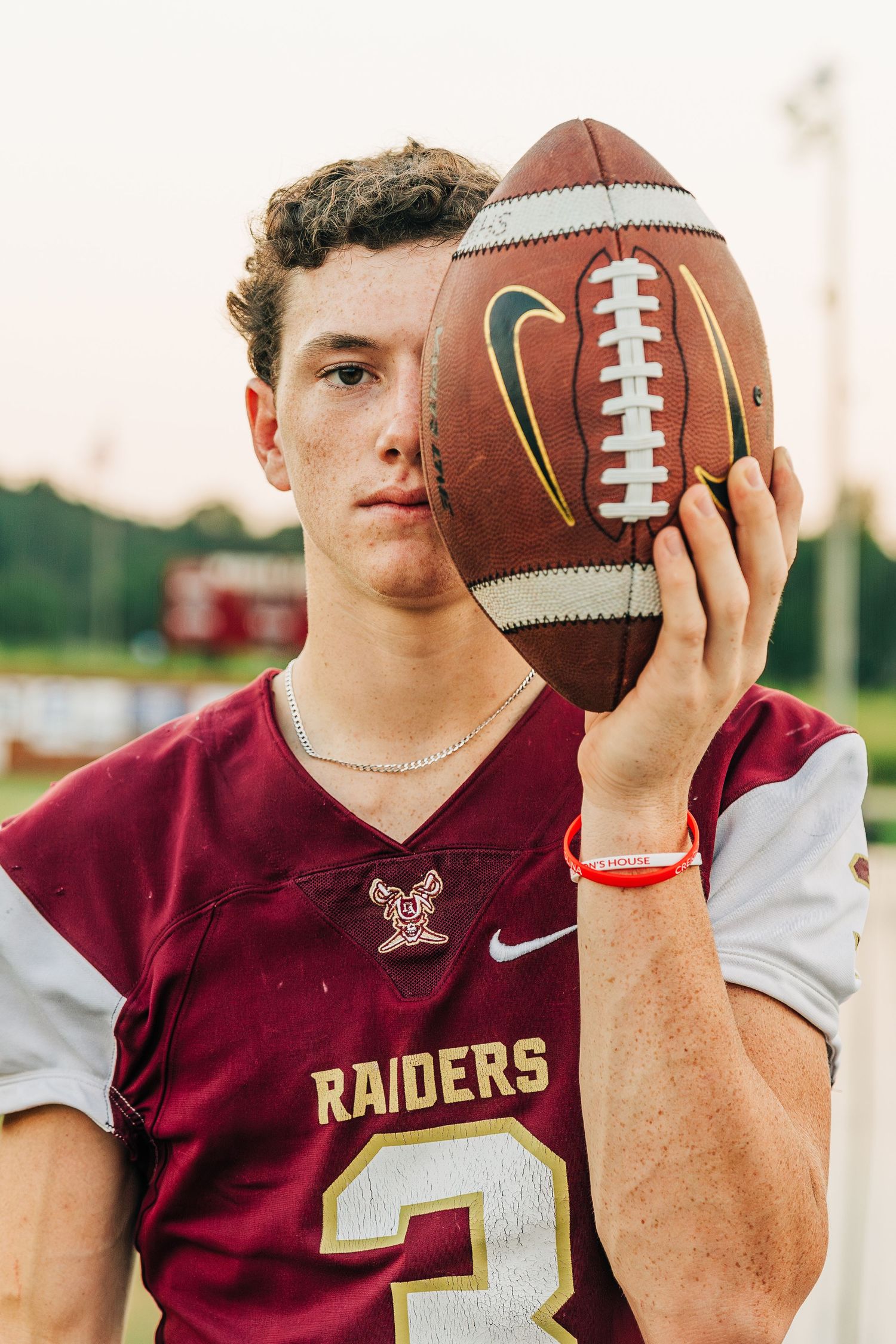 Sports action photo series showing close-up shots of a football player in maroon Raiders jersey holding a football.