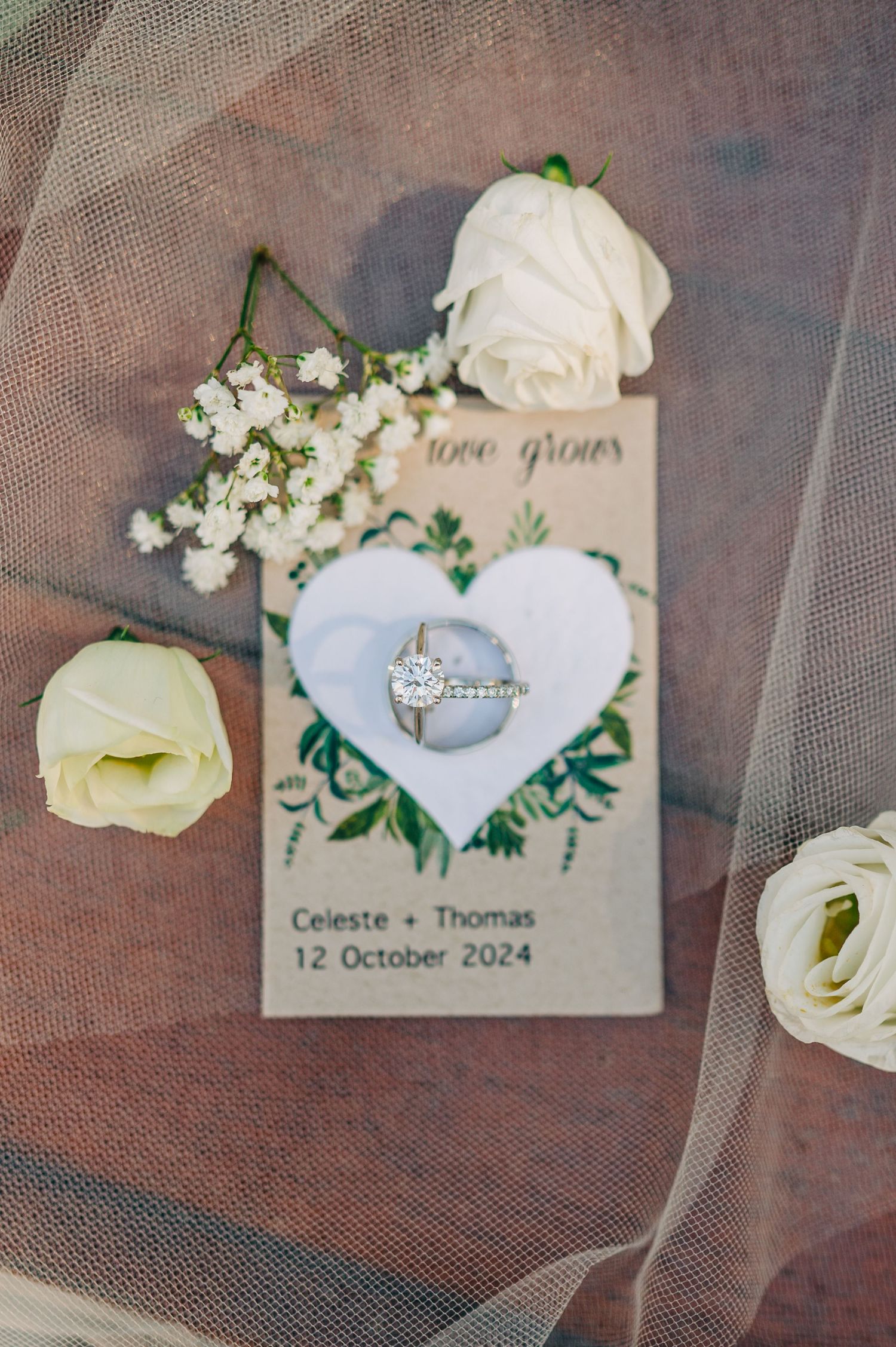 Wedding invitation details with white roses and delicate veil overlay.