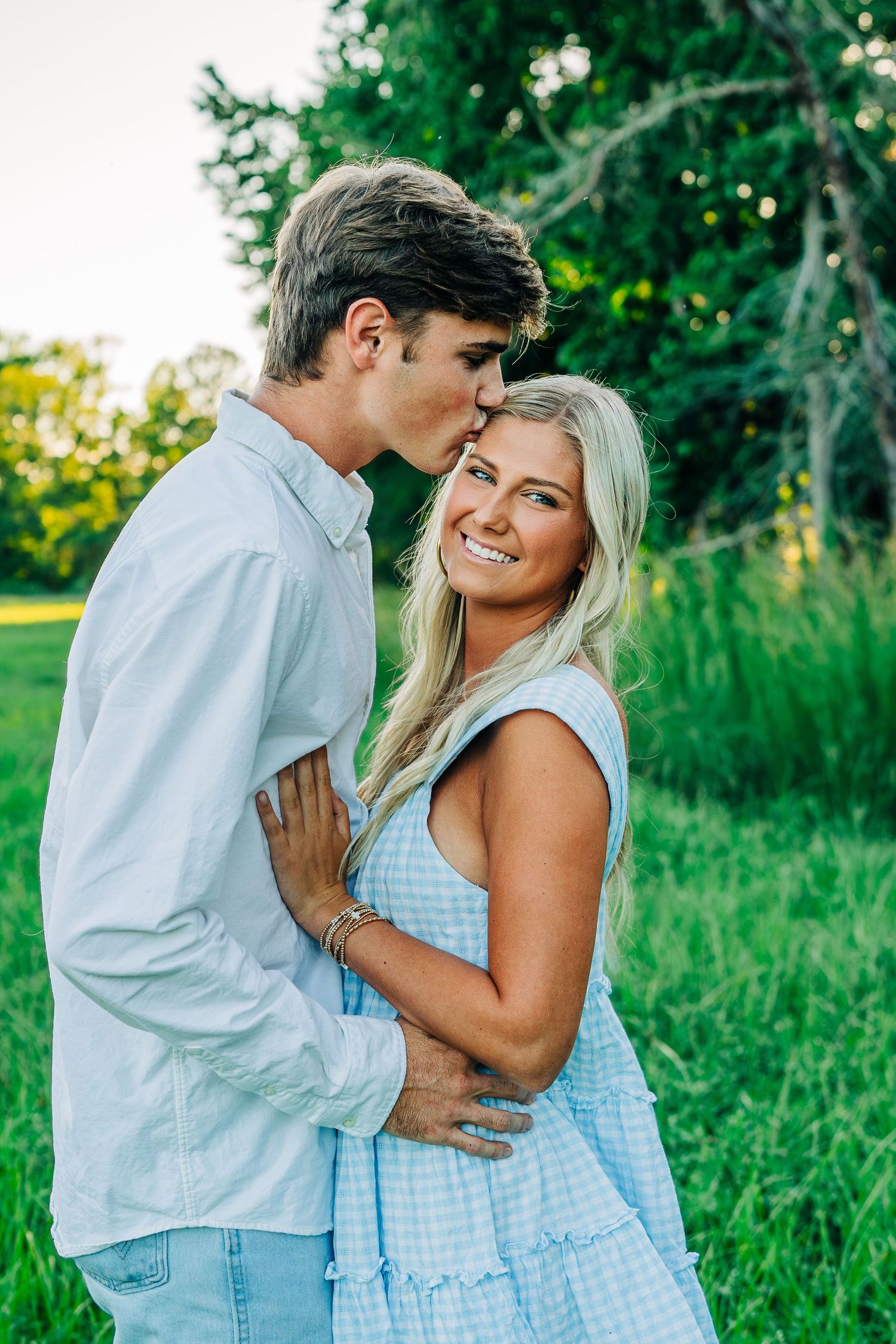 Couple in coordinating blue and white outfits sharing an intimate moment outdoors.