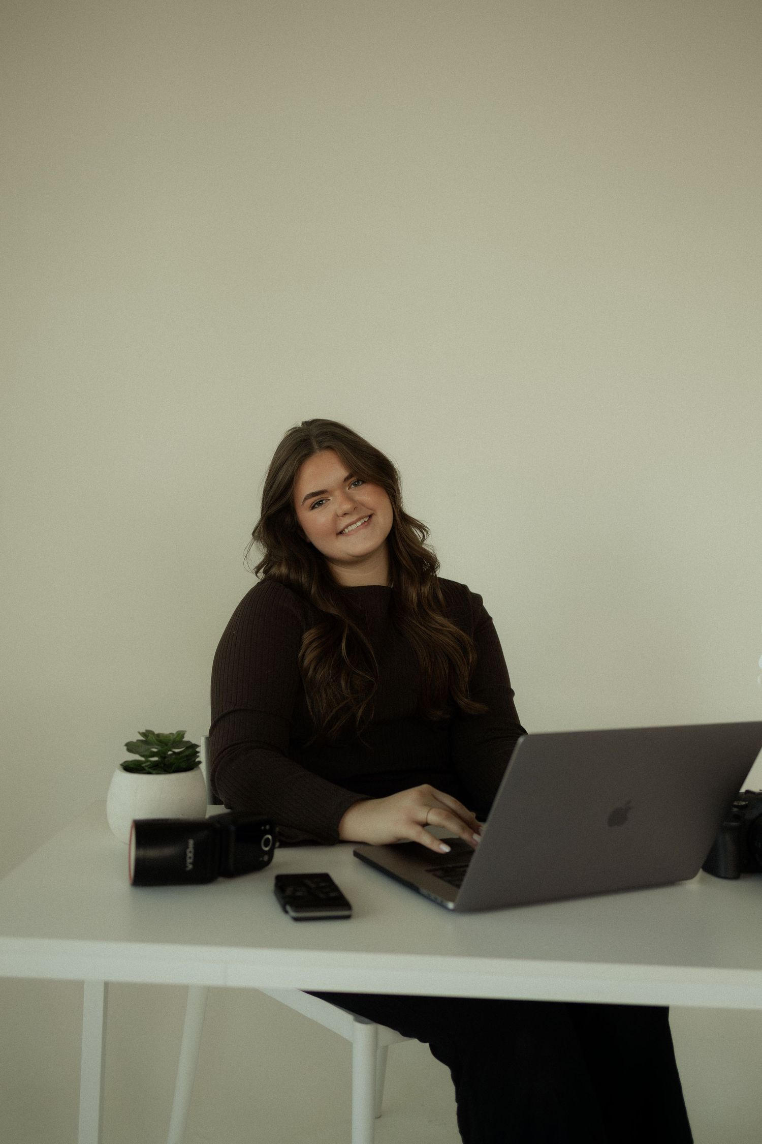 Person working at modern white desk with laptop and phone showing various expressions.