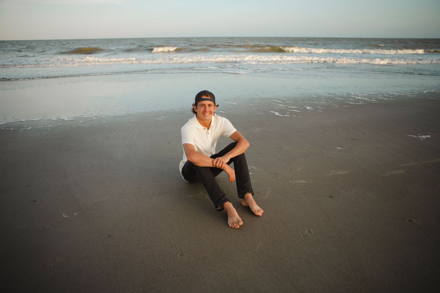 Senior Portrait of Ayden class of 2025. Location Bradley Beach Hilton Head Island, SC.  Ayden sitting and smiling for a photo at the beach.