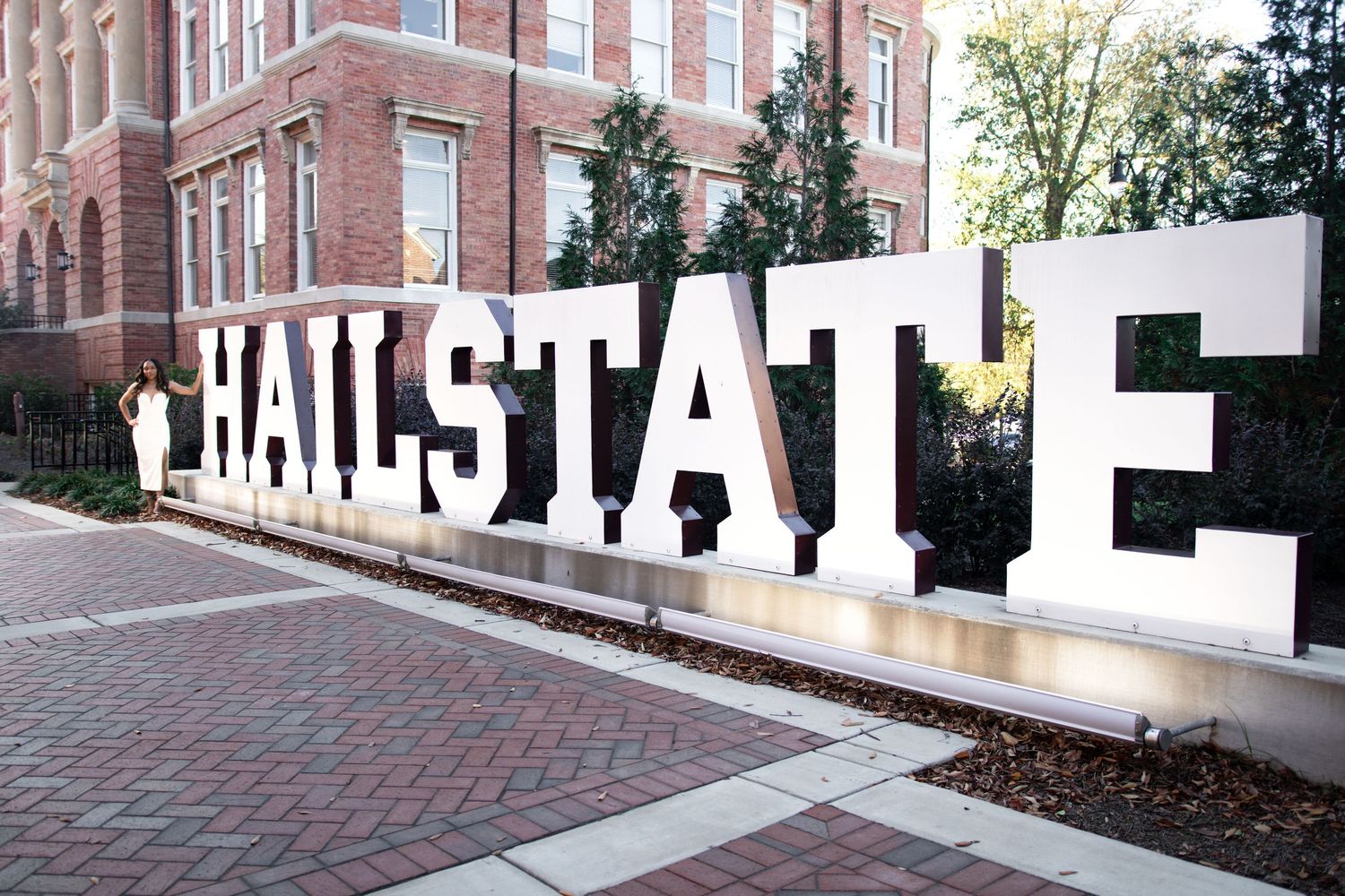 Large white HAILSTATE letter sign on Mississippi State University brick campus pathway.