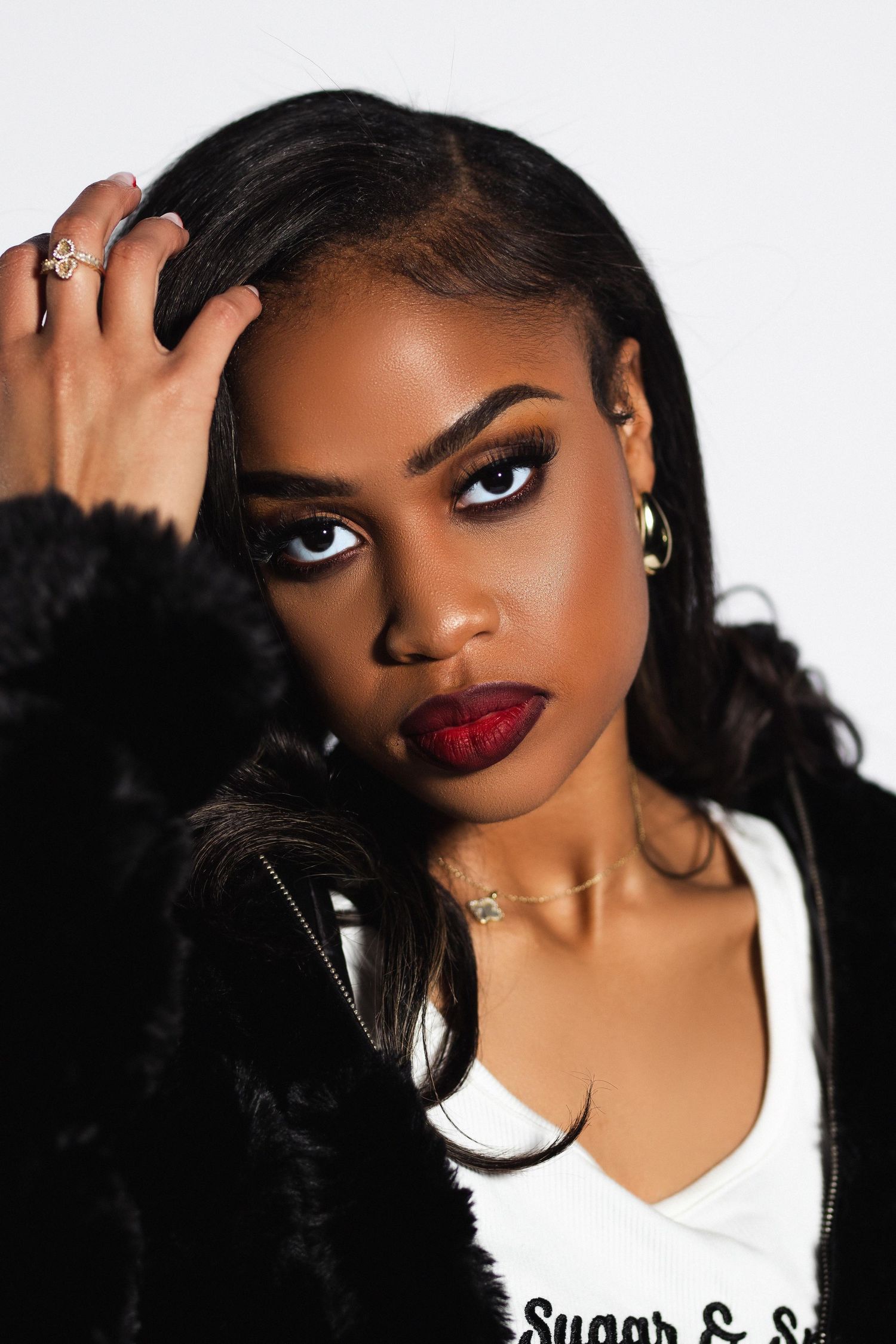 Close-up portrait of woman in black fur coat with red lips and gold jewelry.
