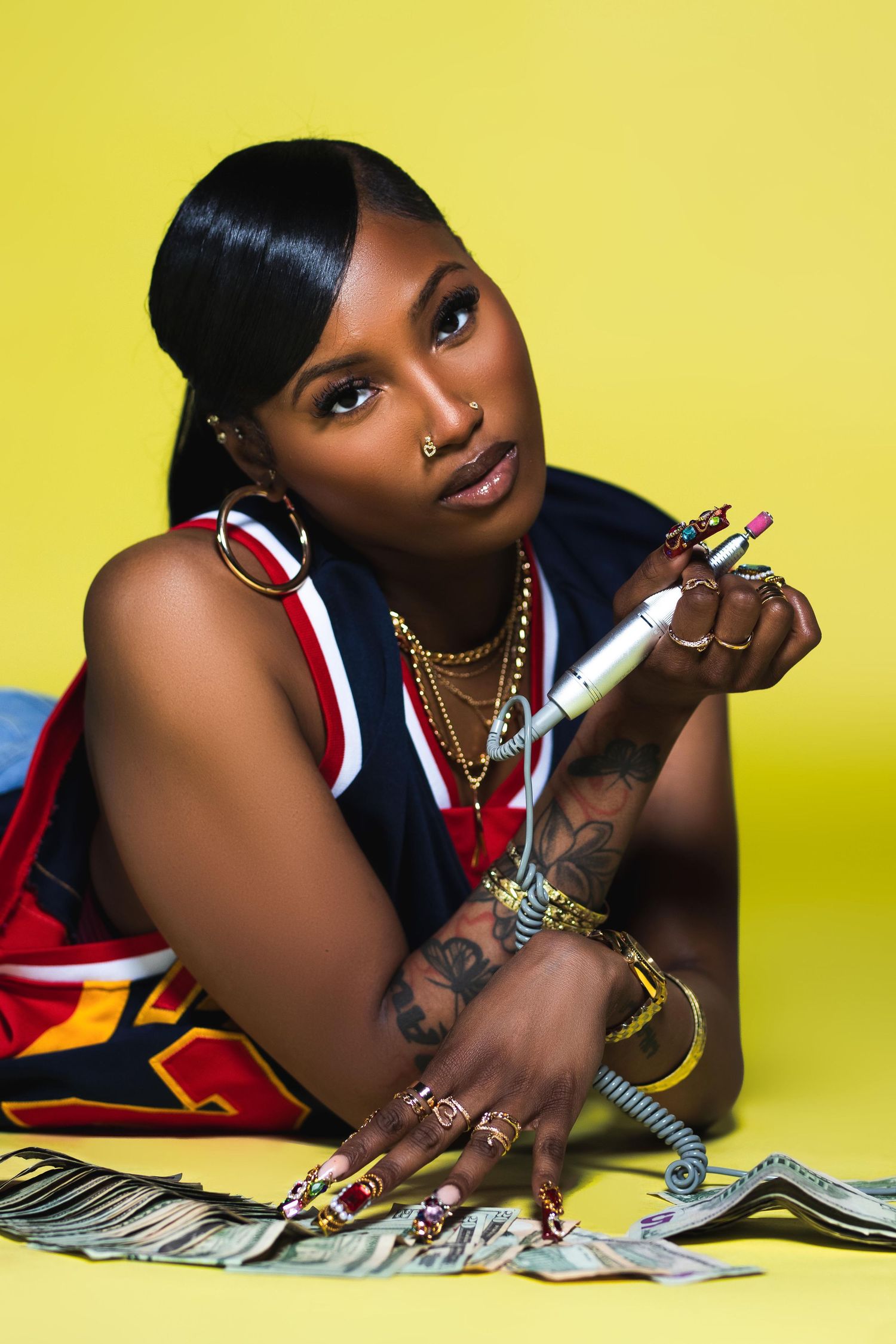 Woman in McDonald's jersey with tattoos poses with lipstick and cash on yellow background.