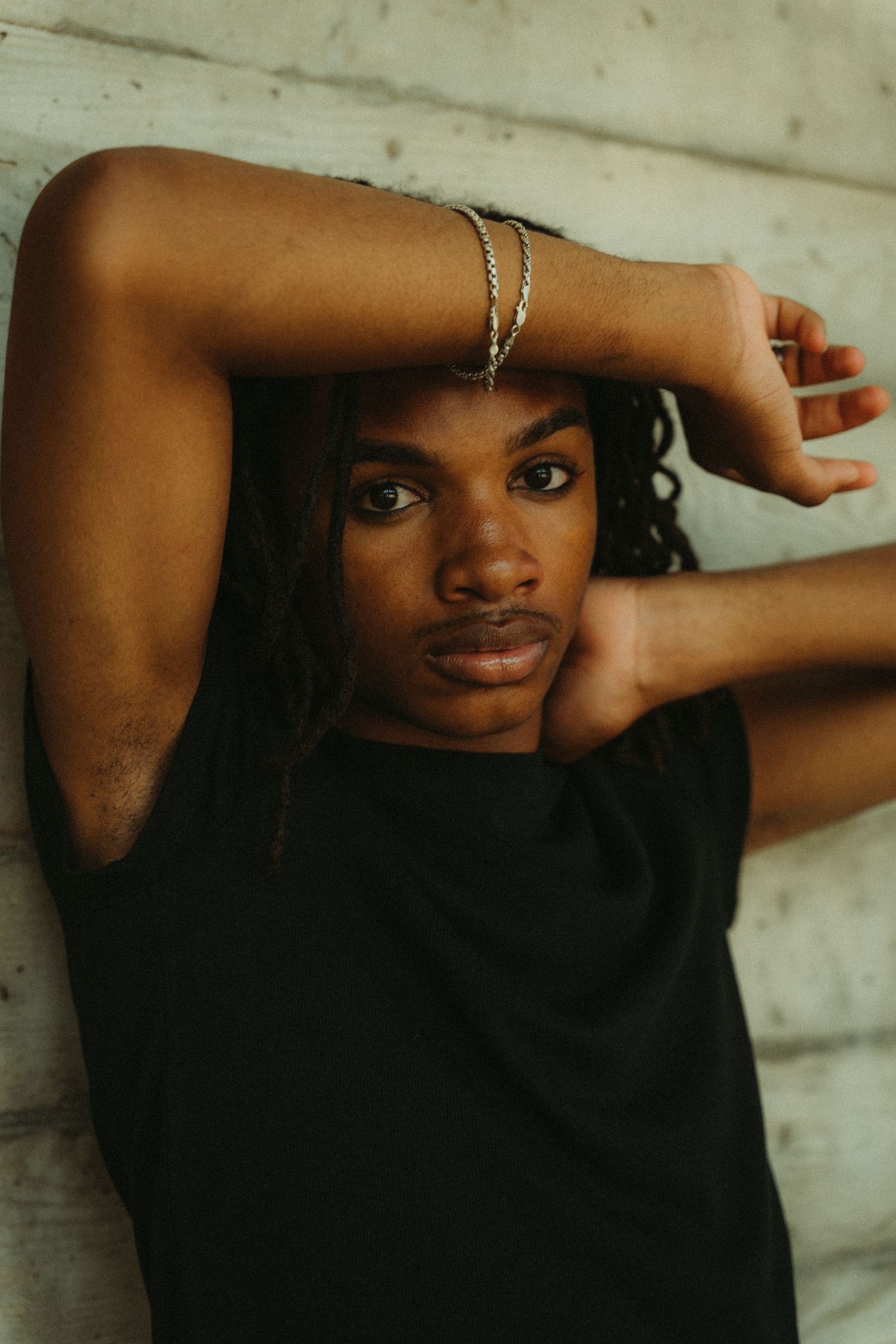 A creative self-portrait sequence showing a person's graceful hand and arm movements against a white wall.