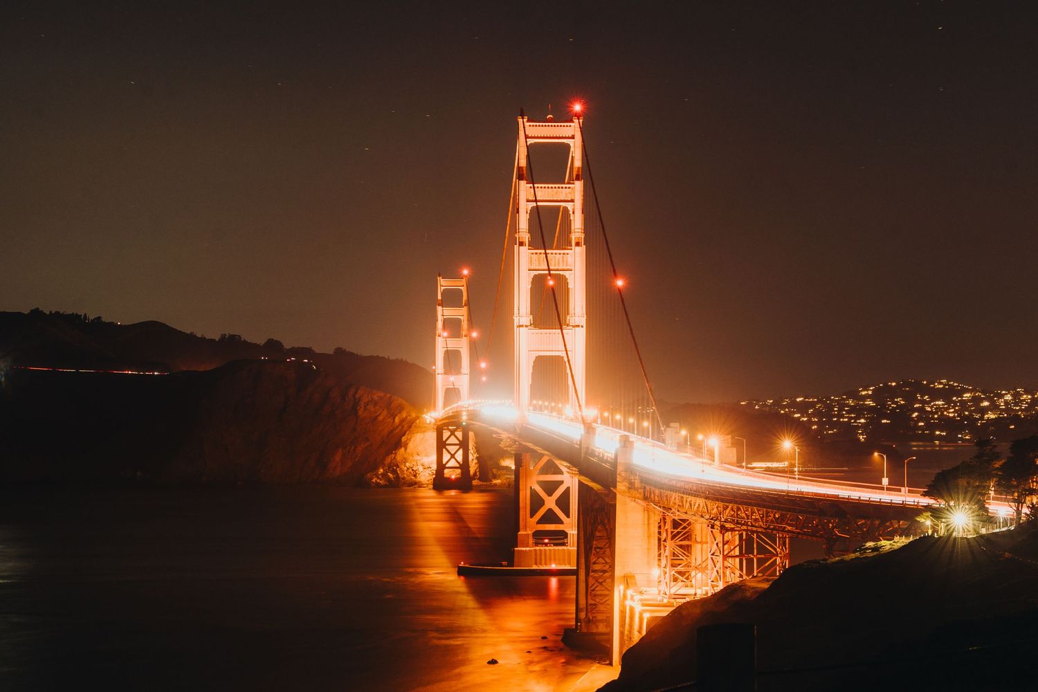 Six long exposure night photographs showing the Golden Gate Bridge illuminated in orange against a dark sky and bay.