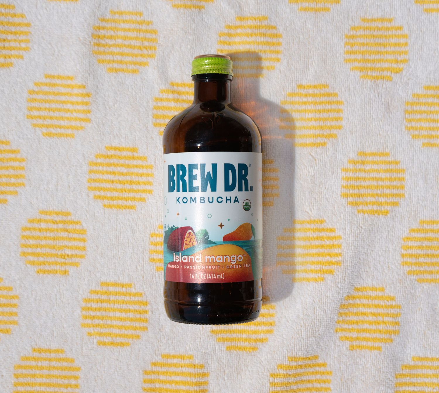 Glass bottle of cold brew coffee concentrate standing against a yellow polka dot patterned background.