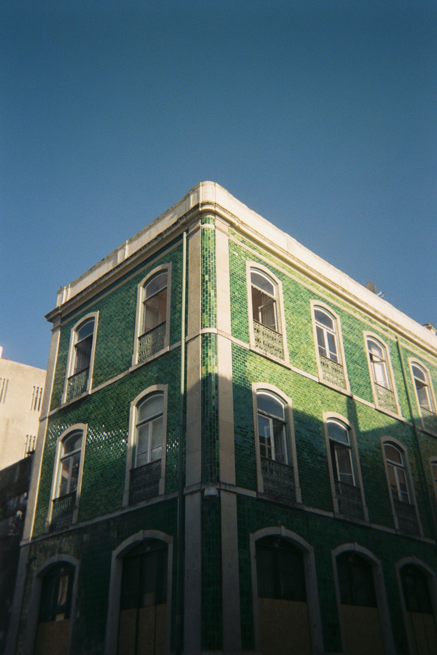 The outside of a beautiful green tile building in Portugal at sunset