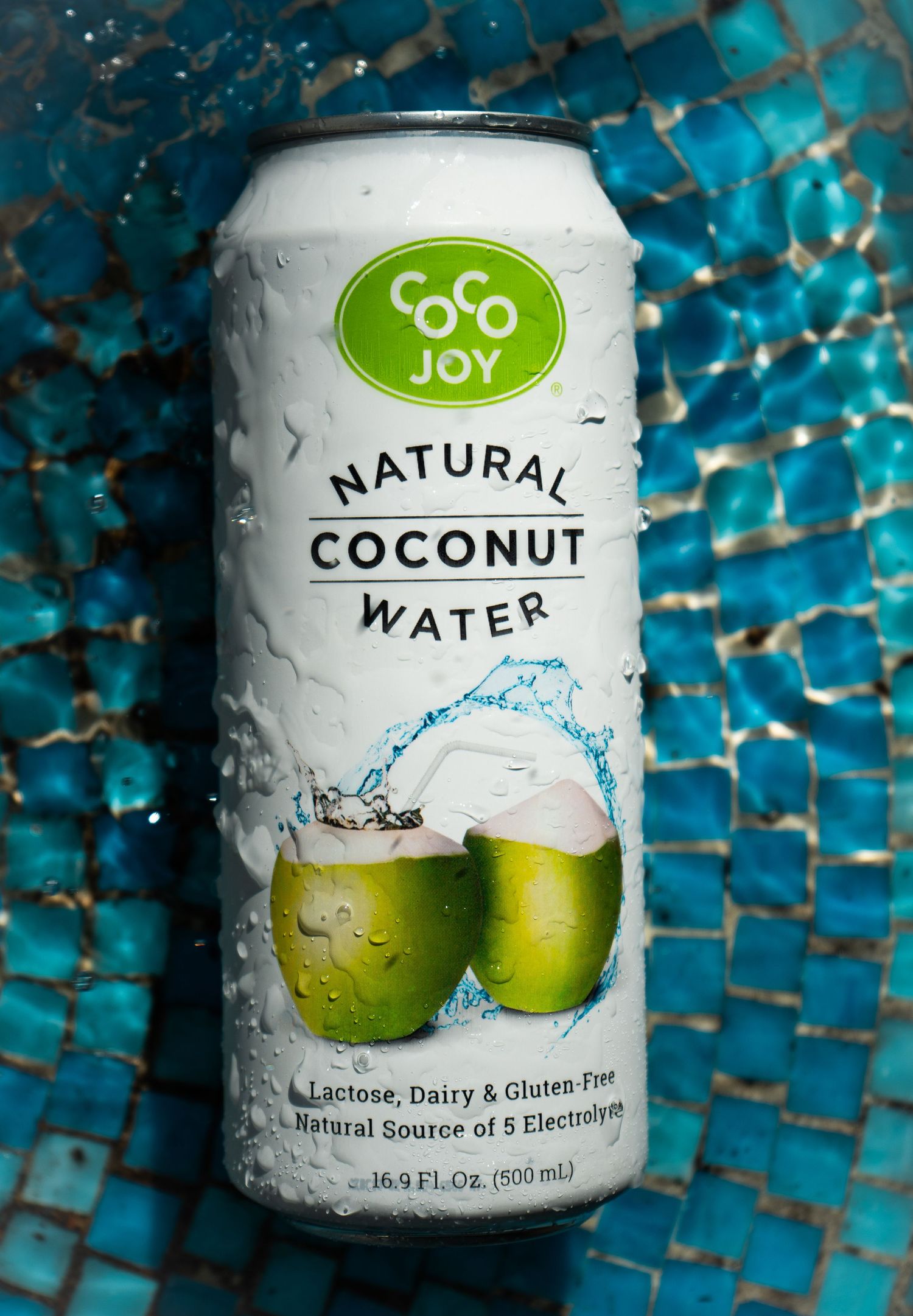 Cold can of Coco Joy coconut water displaying fresh coconuts on the label with water droplets.