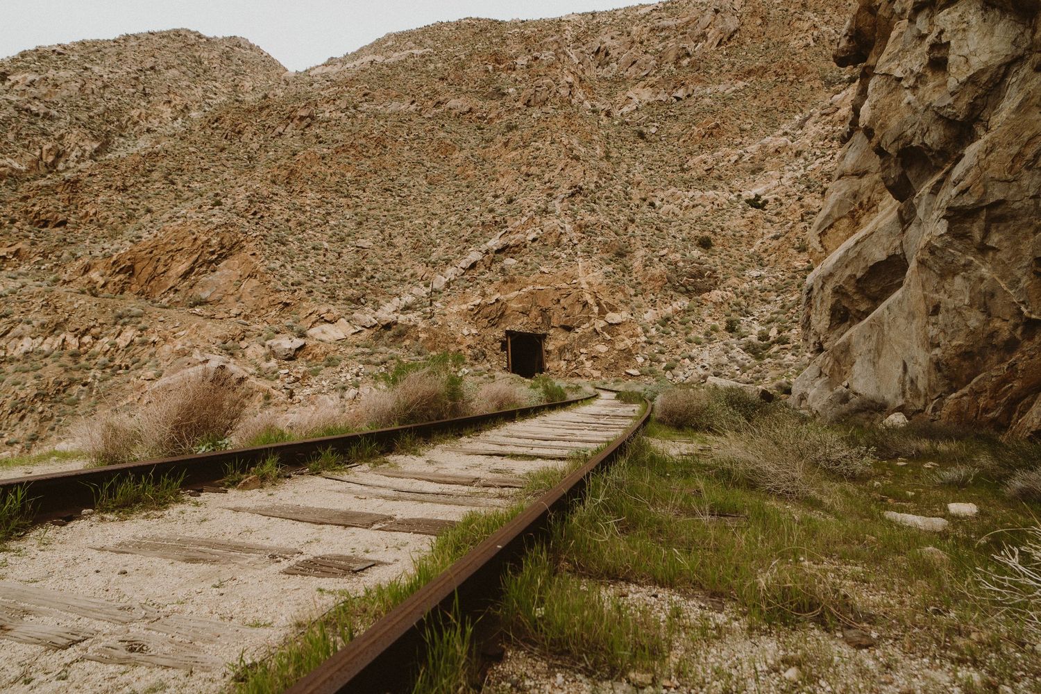 Ancient stone steps wind through a rocky desert landscape alongside a narrow water channel in arid mountains.