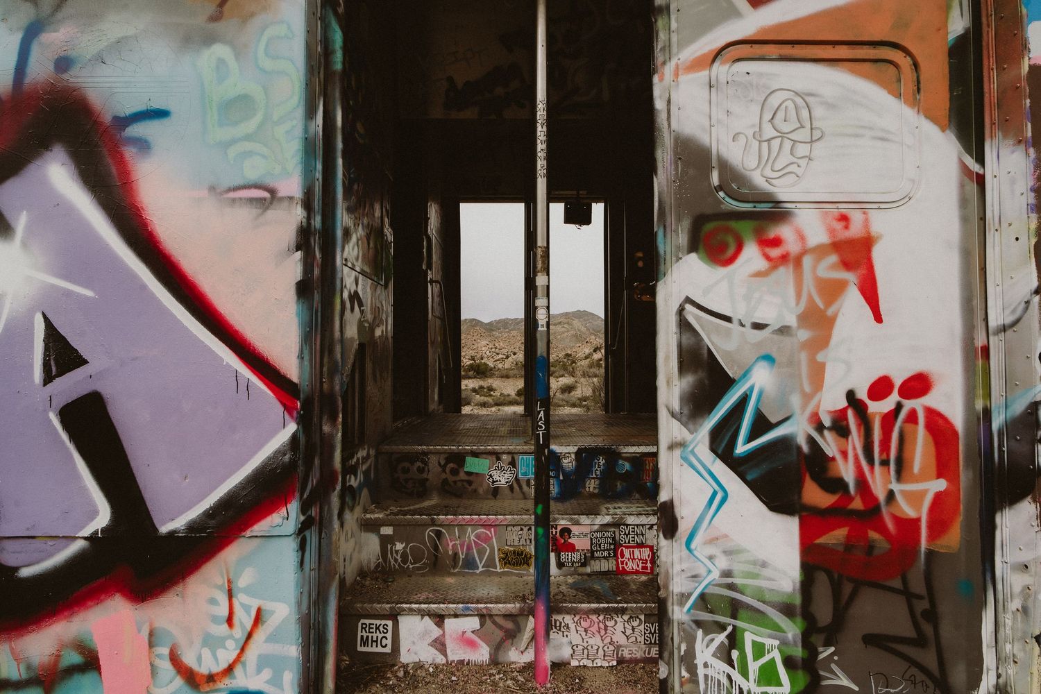 Colorful graffiti art covers a wall with abstract designs and letters in vibrant spray paint colors.
