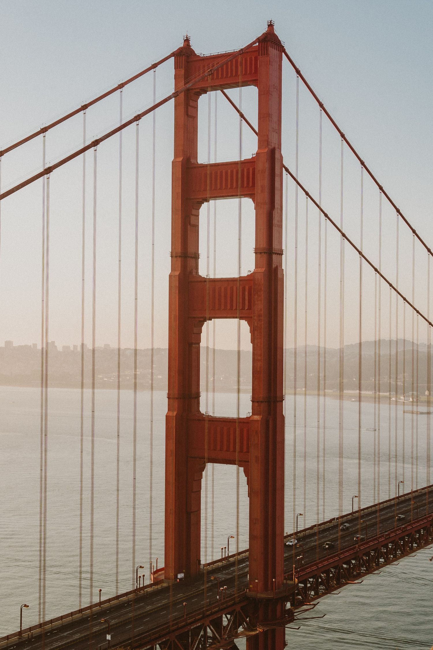 Close-up view of the iconic Golden Gate Bridge's red towers and suspension cables against a foggy San Francisco Bay.