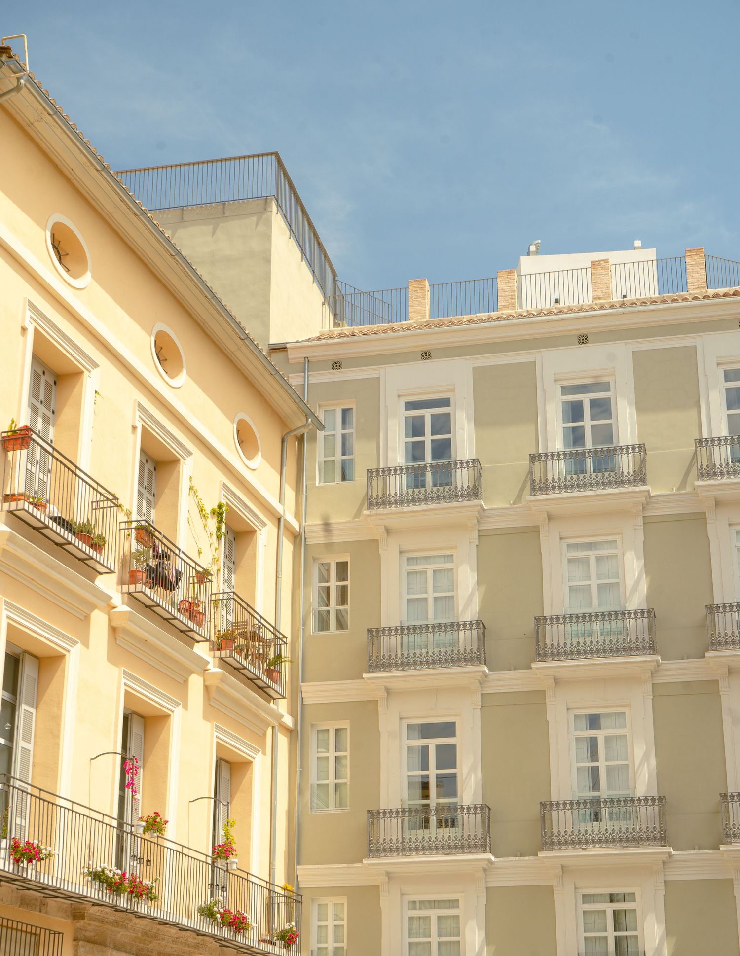 Modern cream-colored apartment building with multiple balconies and ornate architectural details in Mediterranean style.