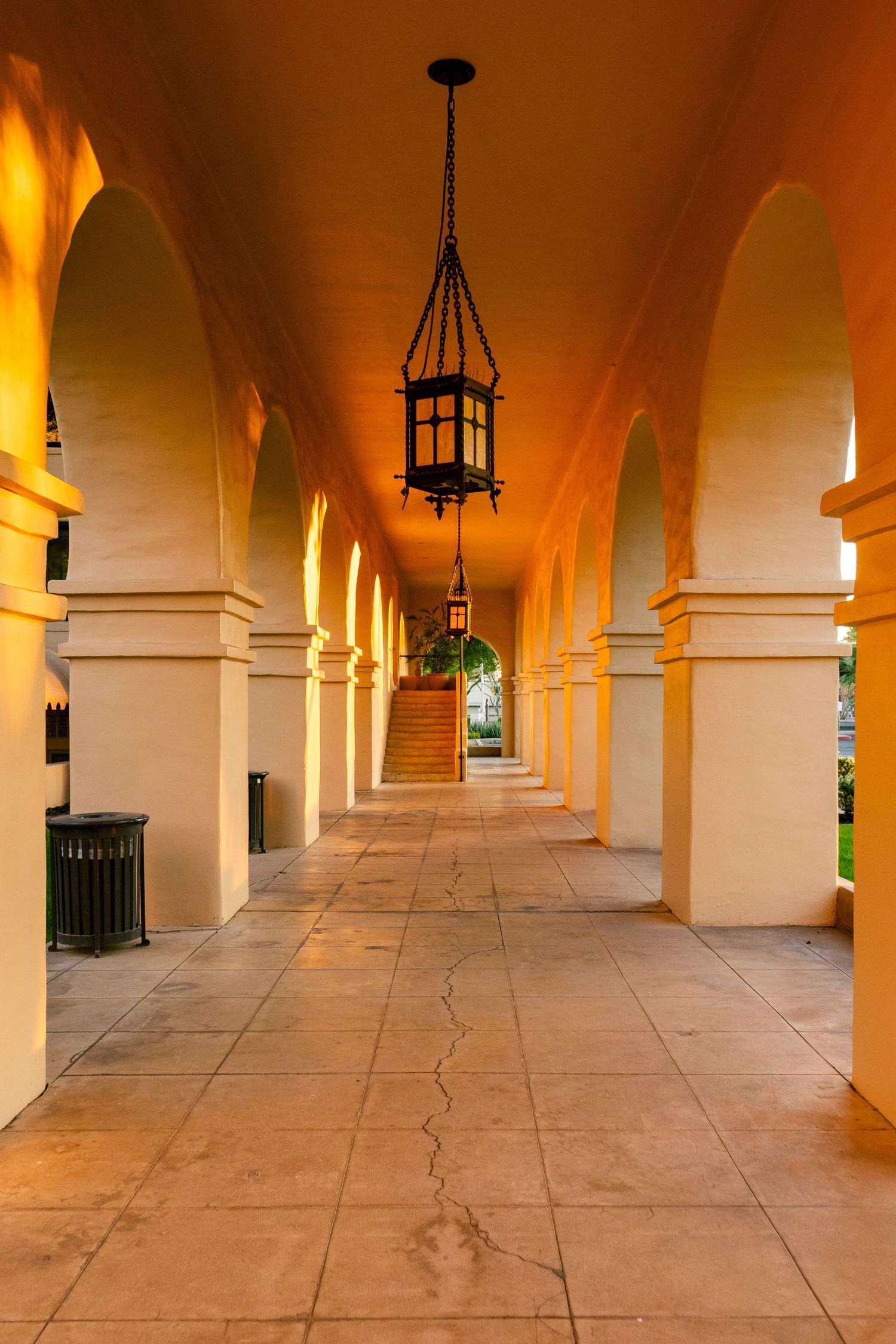Arched colonnade walkway with hanging lanterns and warm lighting.