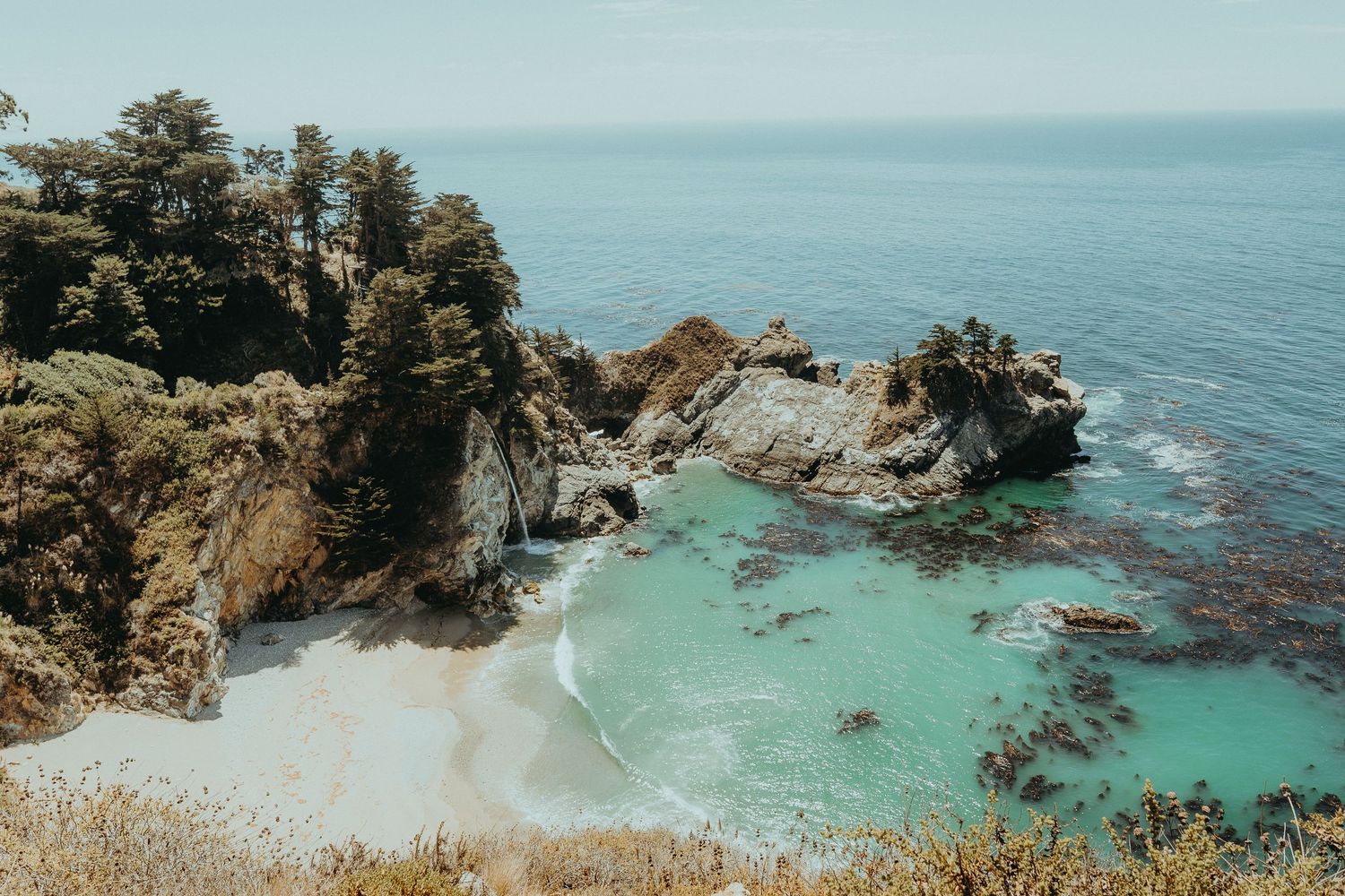 Scenic panorama of rugged coastal cliffs and turquoise waters along Big Sur's Pacific coastline in California.
