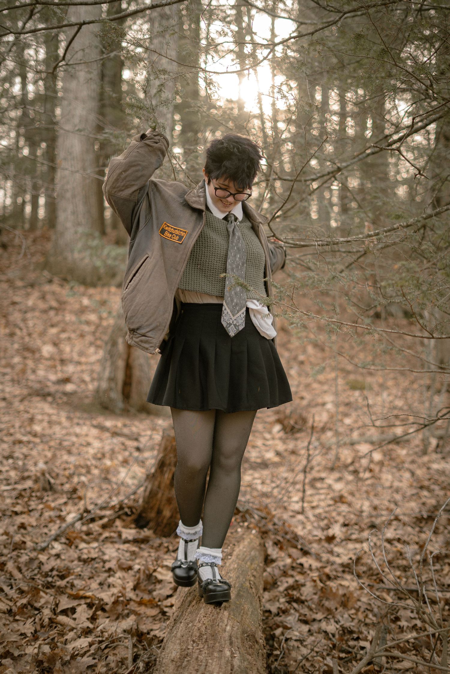 A person wearing gray clothes and socks sits in different poses on a fallen tree trunk in an autumn forest setting.