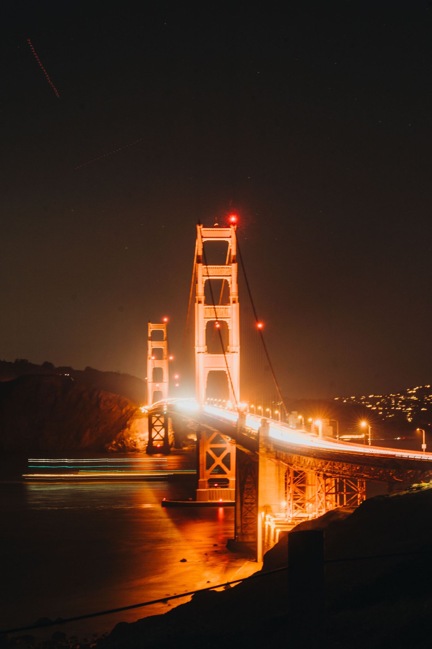 A series of nighttime photographs showing the Golden Gate Bridge illuminated in orange against the dark San Francisco Bay.