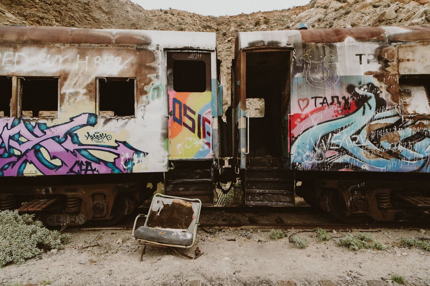 A series of abandoned buildings covered in graffiti and street art create an urban exploration scene.