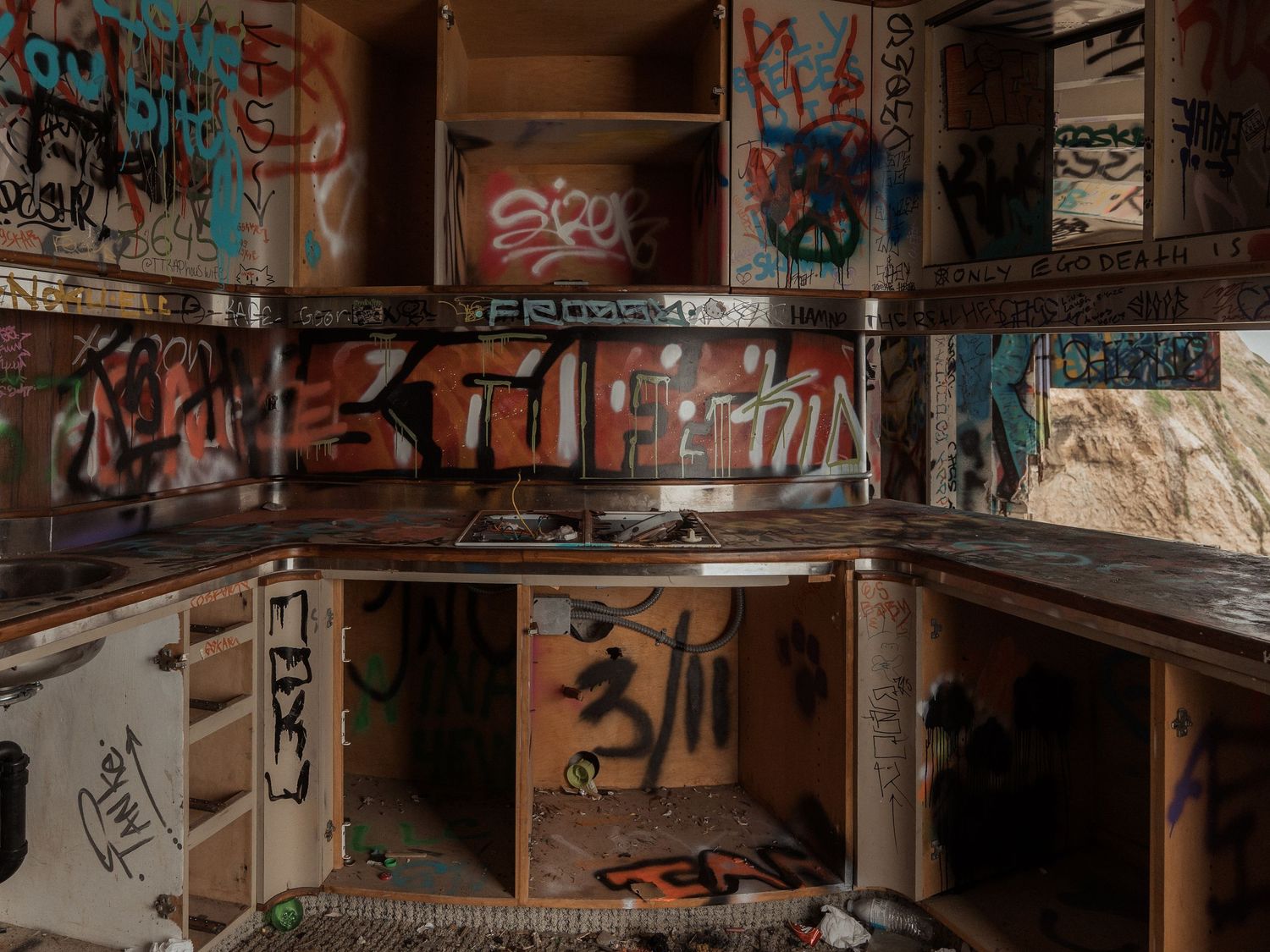 Urban graffiti covers the walls and surfaces of an abandoned industrial building interior with colorful spray paint designs.