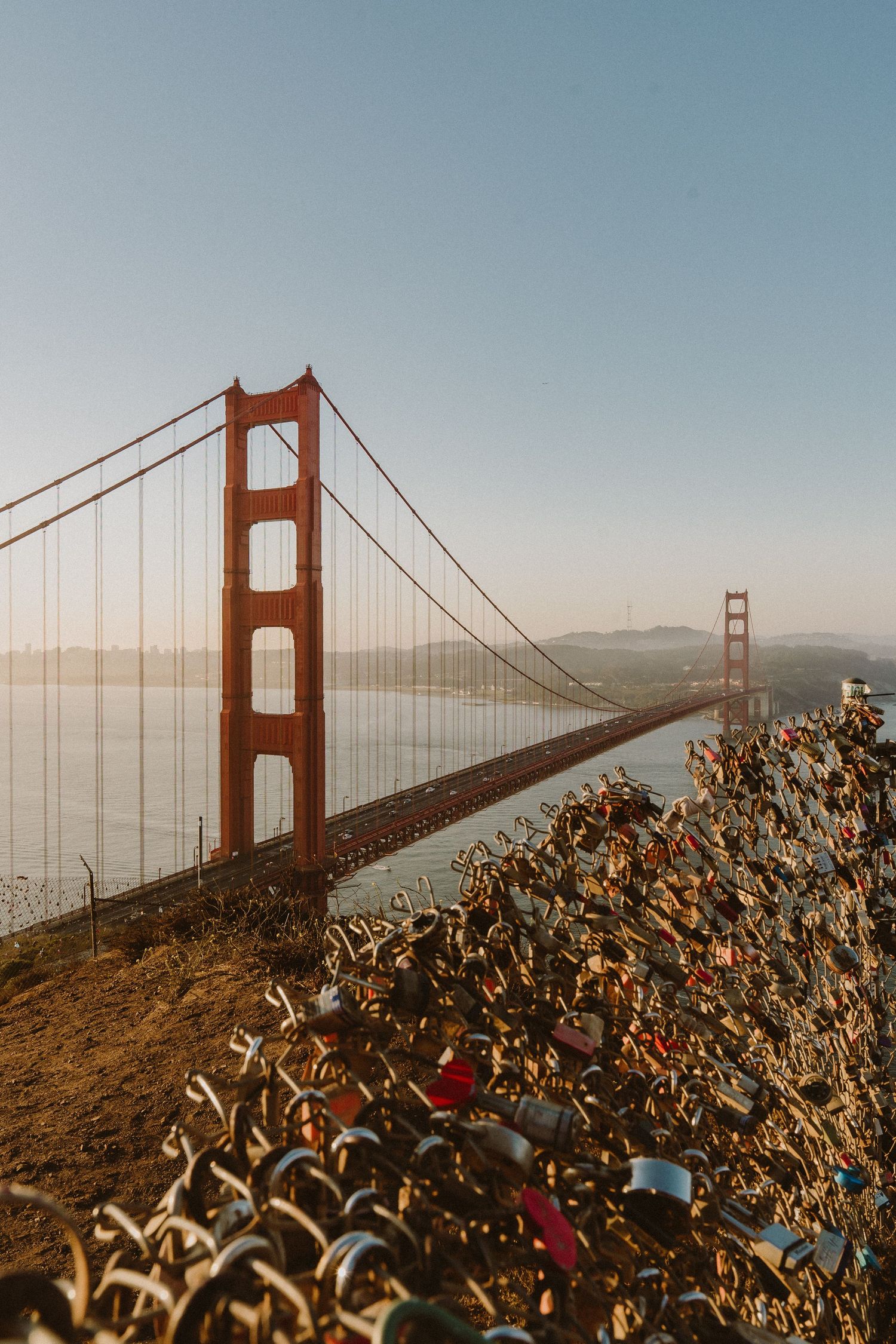 Golden Gate Bridge towers rise above coastal vegetation against a blue sky in San Francisco.