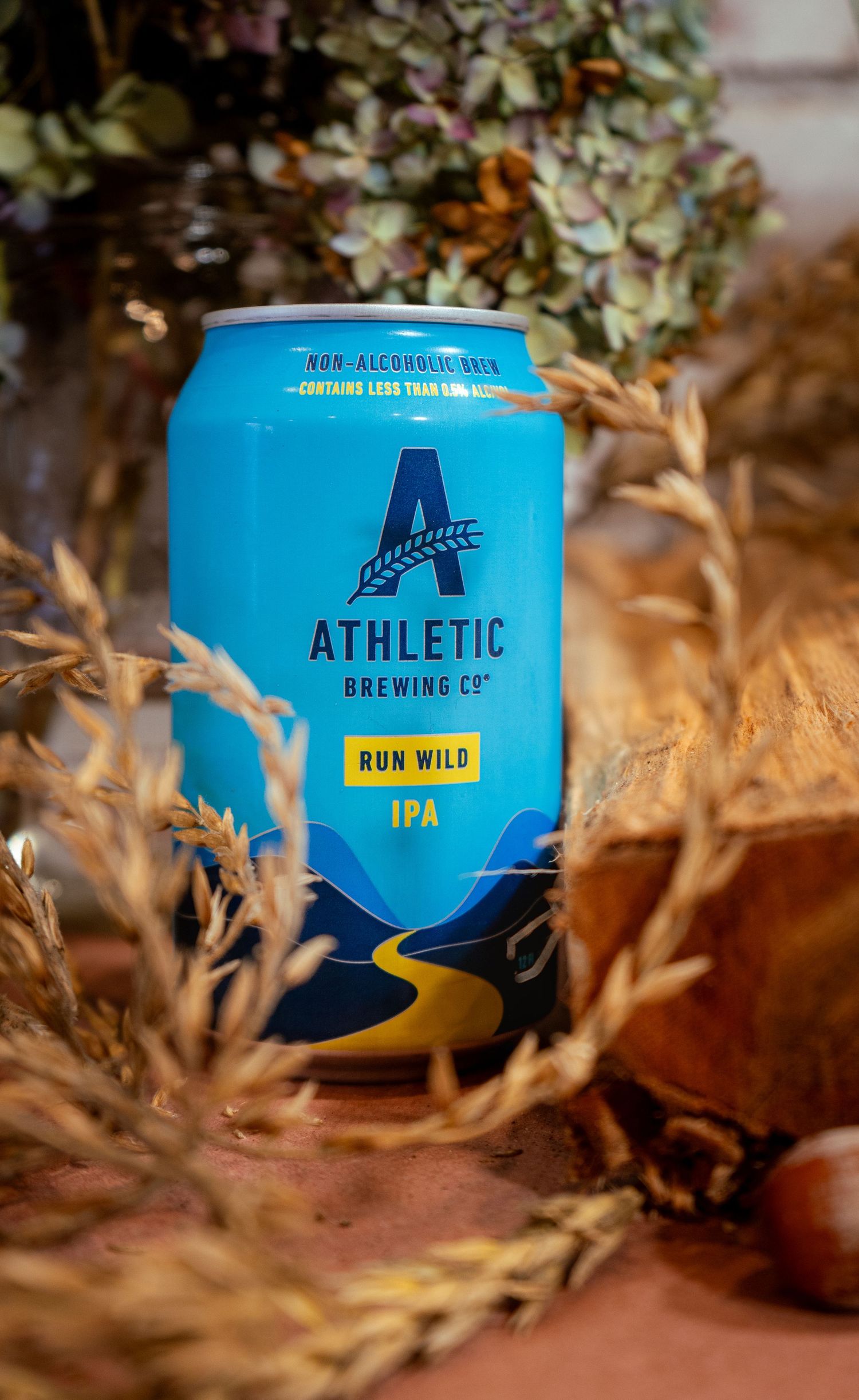 Athletic Brewing Company's Run Wild IPA can nestled in dried autumn leaves.