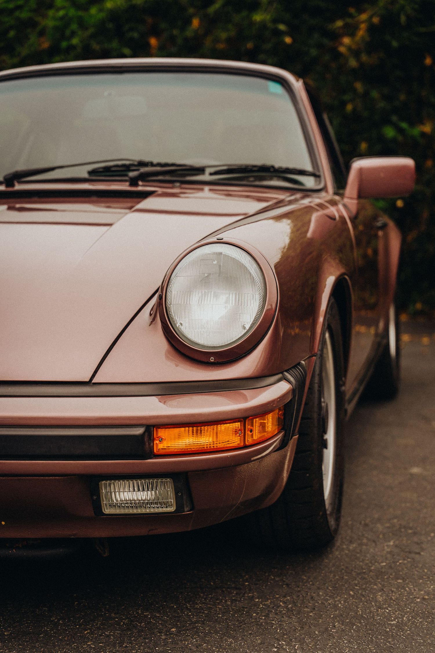 Close-up view of a vintage copper-colored Porsche 911's front end showing headlight and turn signal detail.
