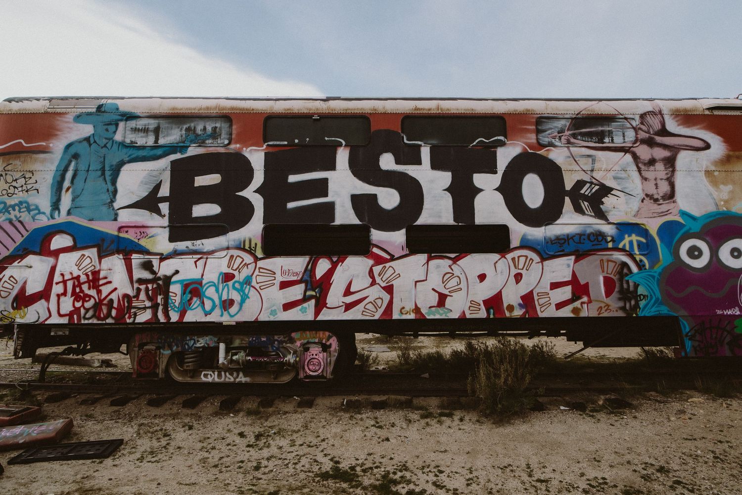 Colorful graffiti art spans across a long concrete wall with urban street art designs and text.