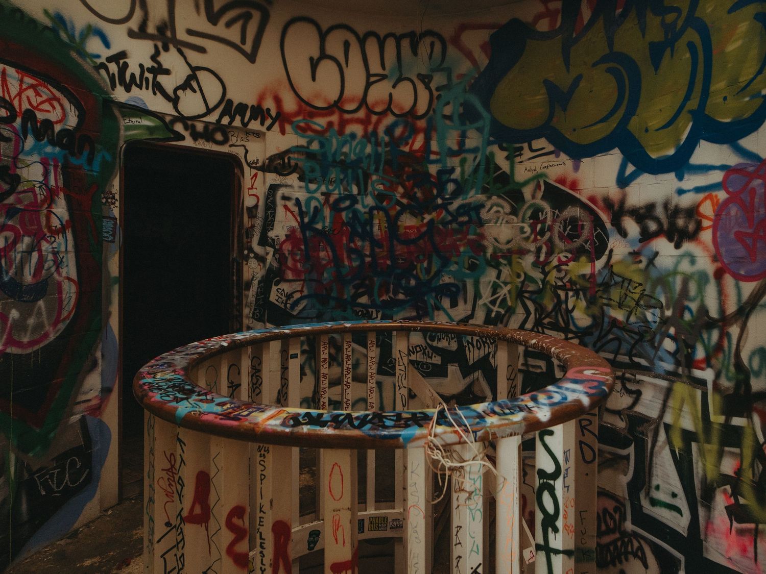 Colorful graffiti art covers multiple walls in an urban alleyway with overlapping tags and designs in vibrant colors.