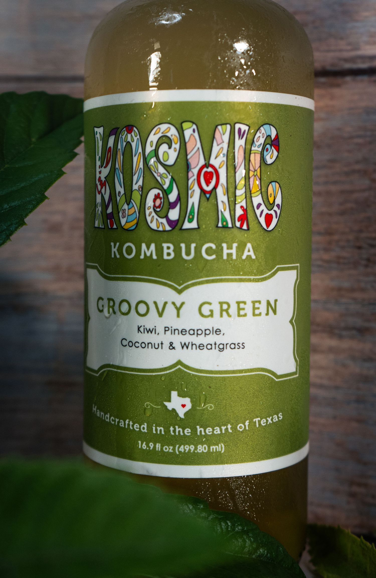 Close-up of Kosmic Kombucha Groovy Green label showing kiwi, pineapple, coconut and wheatgrass ingredients.