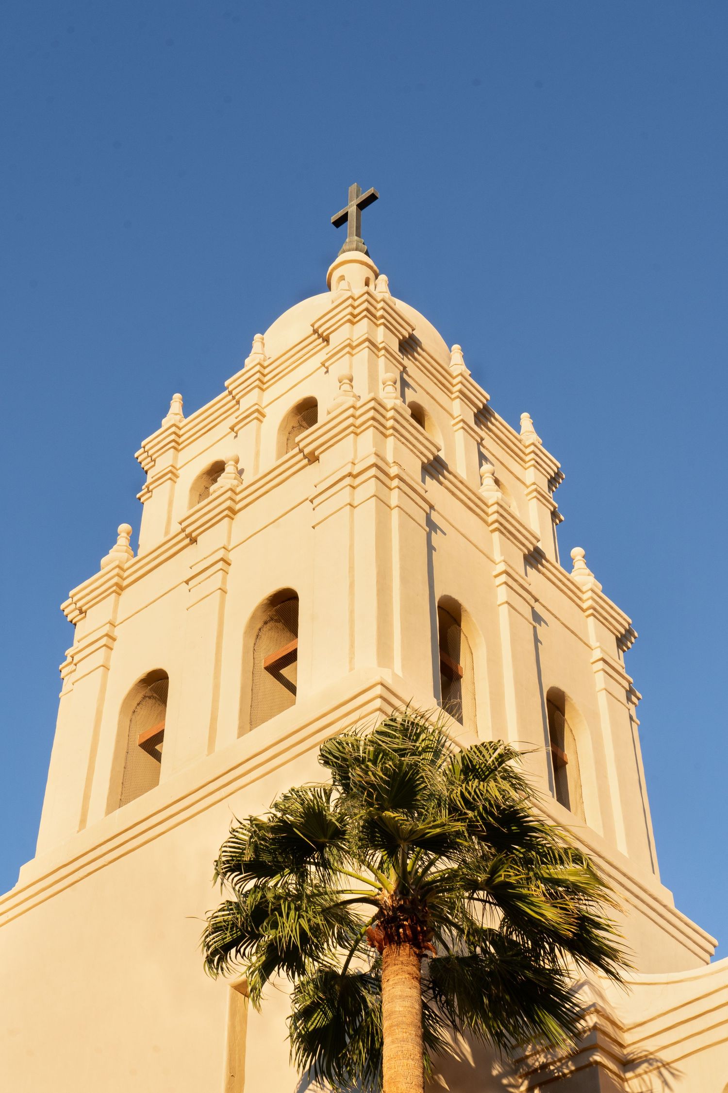 Spanish colonial church towers with white facade against bright blue sky.