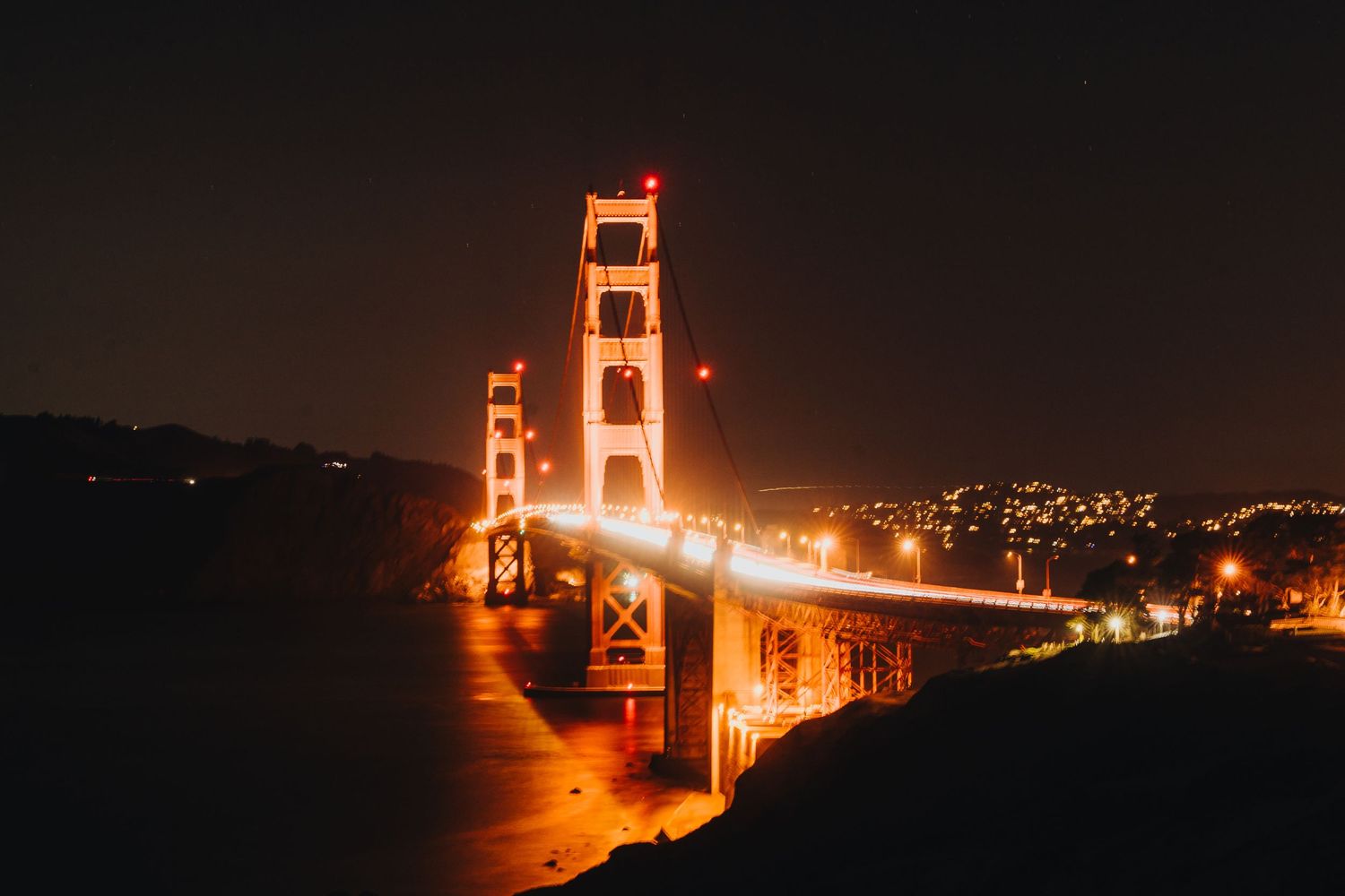 The Golden Gate Bridge towers illuminate the San Francisco Bay at night in a stunning long exposure photograph.
