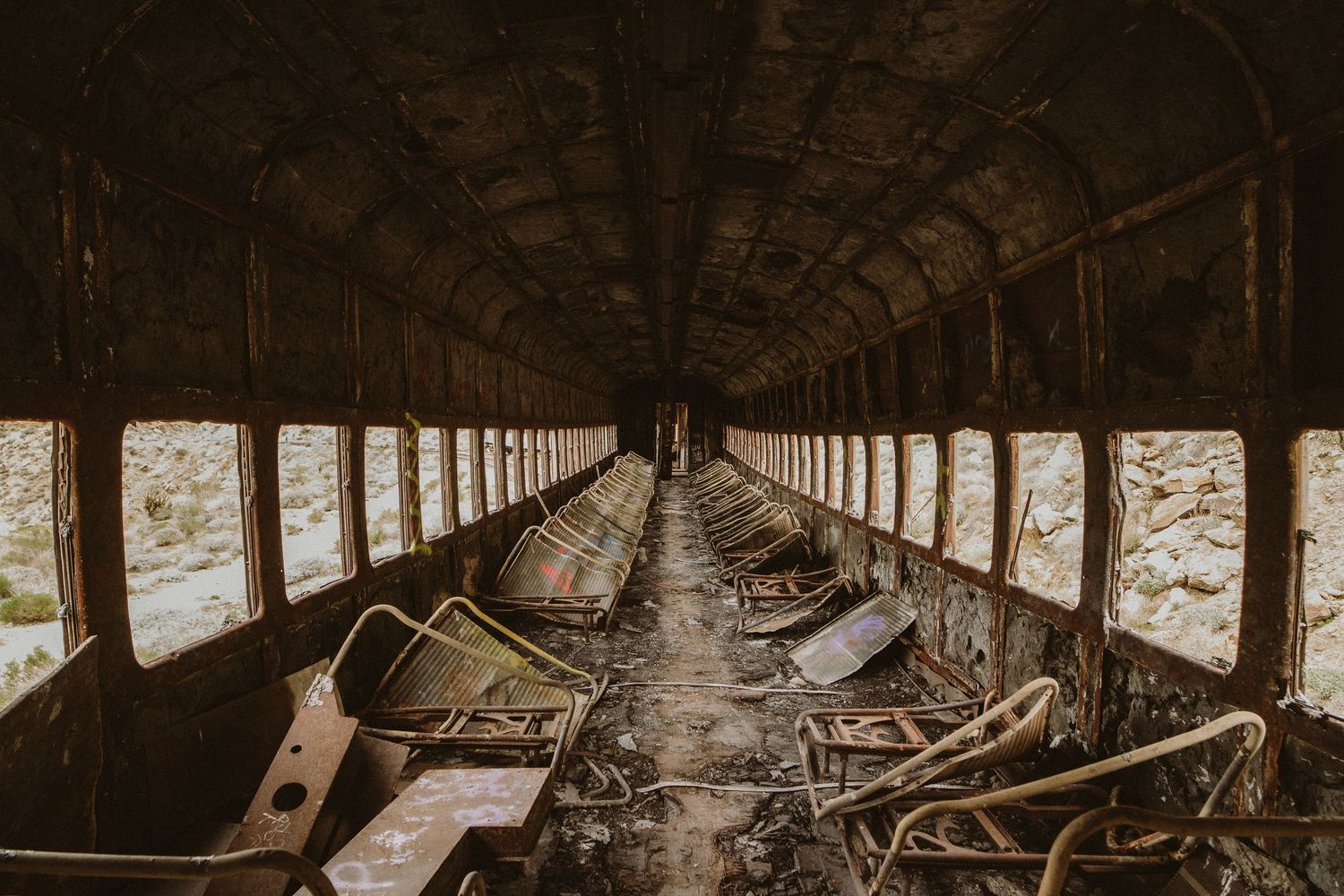 Abandoned railroad tracks and wooden beams extend through a dark tunnel creating an eerie perspective into darkness.