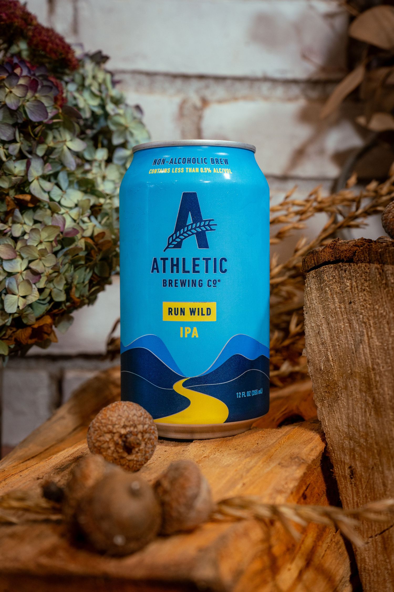Blue can of Athletic Brewing IPA displayed on rustic wooden surface with decorative elements.