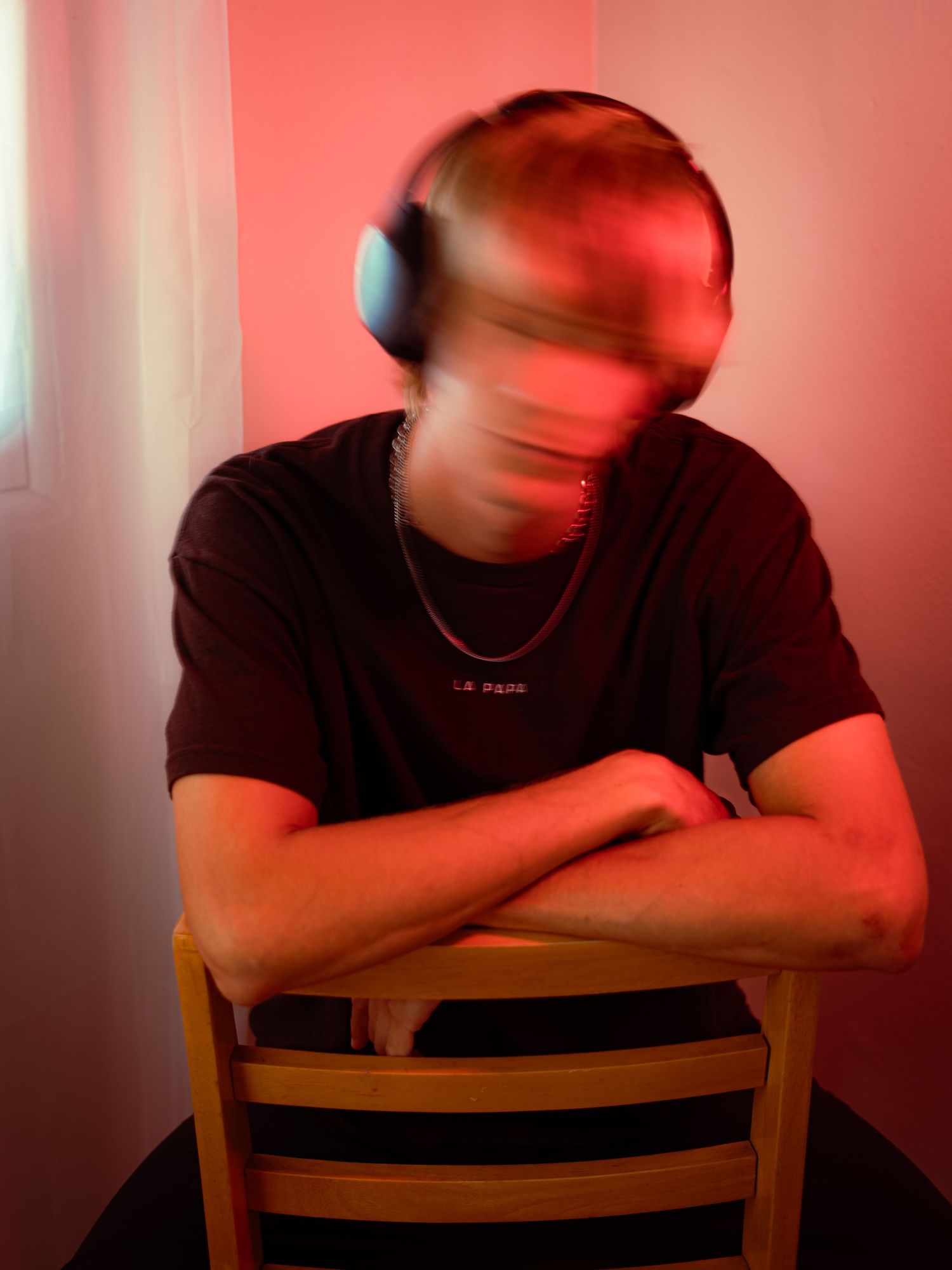 Artistic portrait with motion blur and red lighting of person wearing headphones.