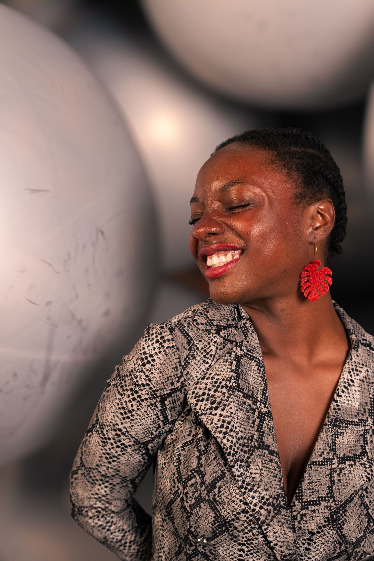 Joyful expression captured in profile wearing snakeskin print and red statement earring.