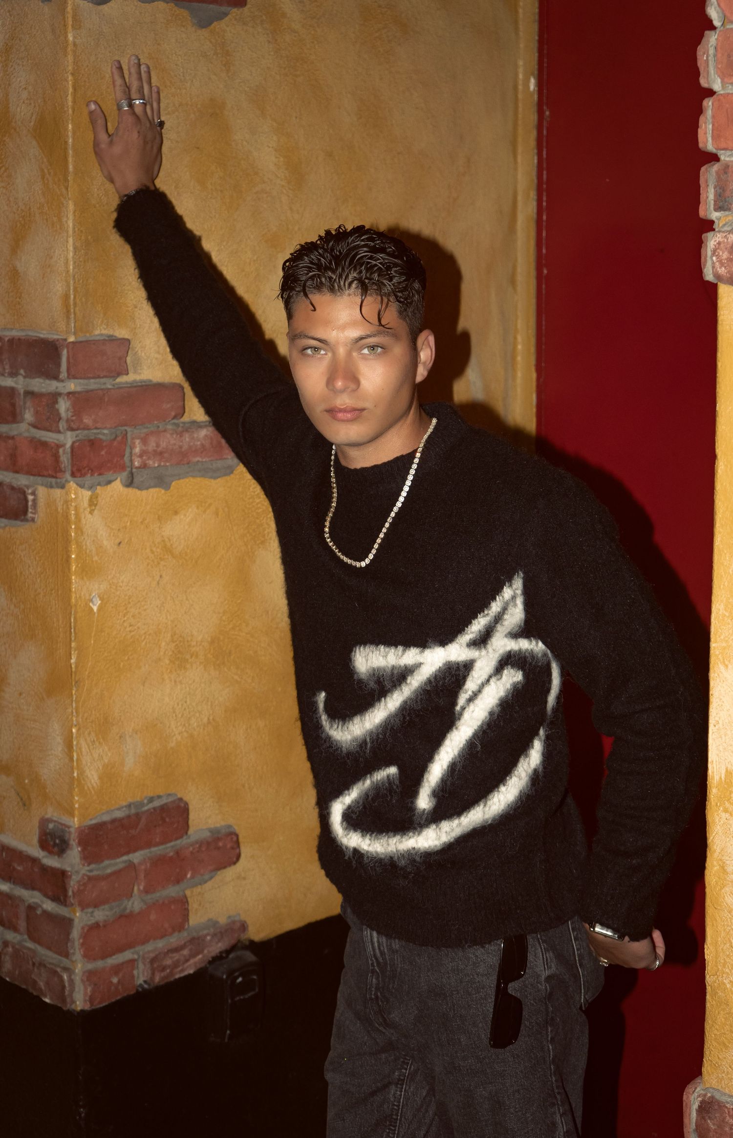 Person in black sweater posing against textured wall in vintage film style photos.