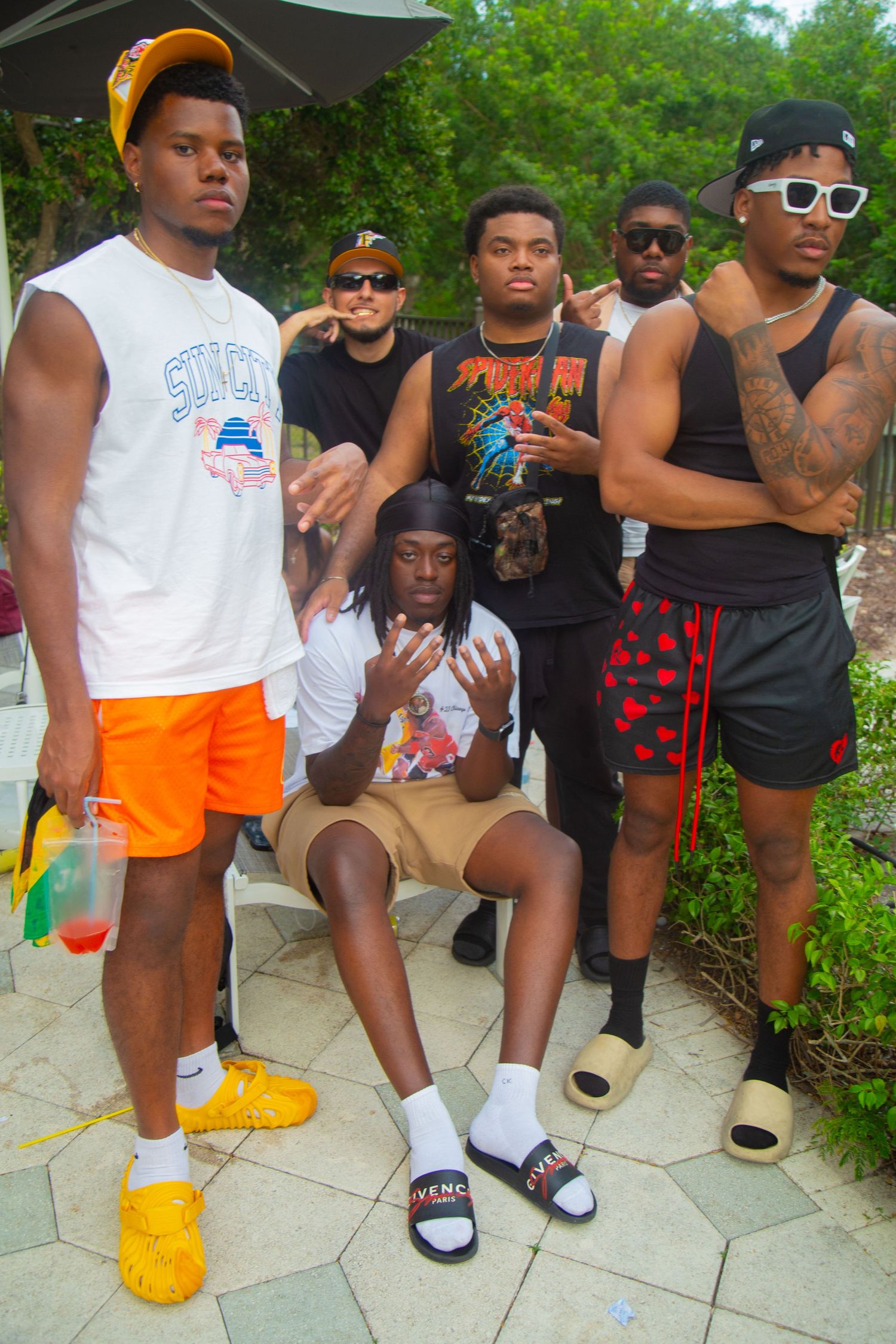 Friends in casual summer attire pose together on outdoor patio.
