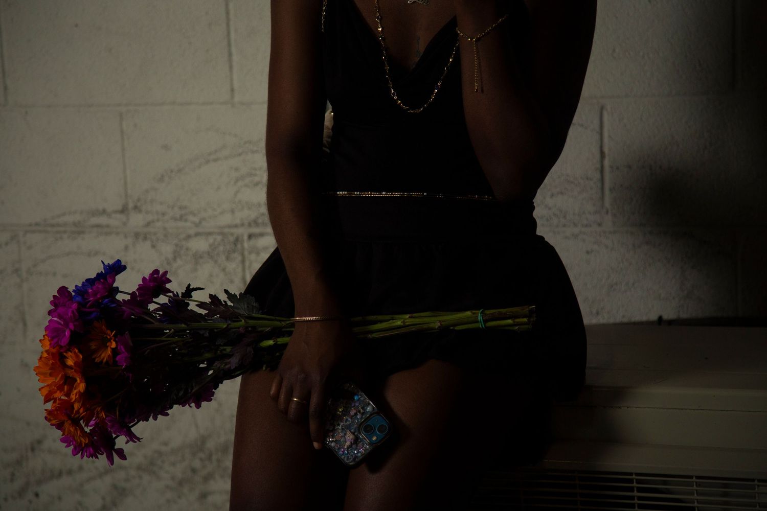 Silhouette holding colorful flowers while sitting in dark setting.
